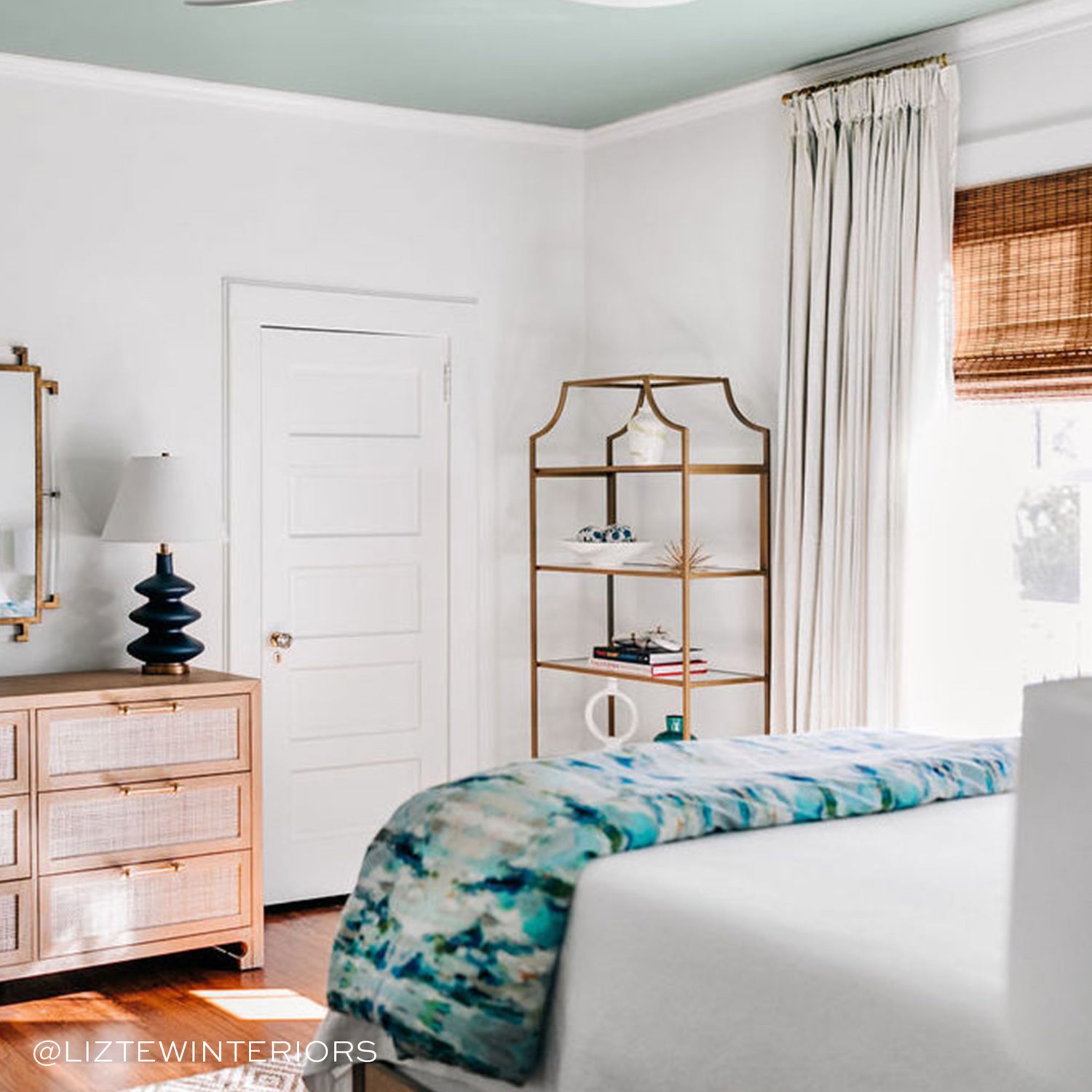 Bedroom styled with Moss Green Geometric Printed Curtains on illuminated window by white bed and wooden dresser in front. Photo taken by Liz Tew Interiors