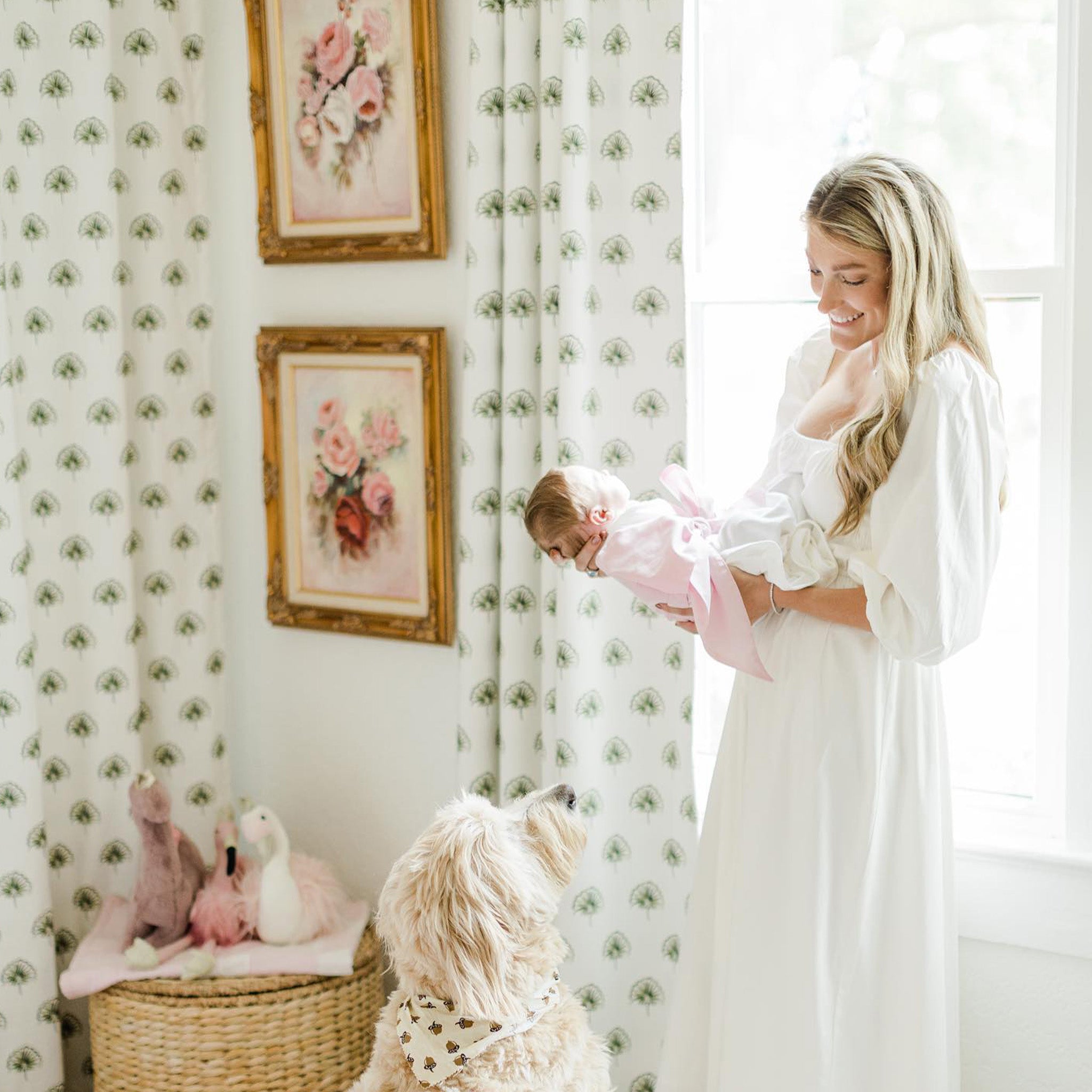 Corner Close-up styled with Green Floral Printed Curtains on illuminated window next to blonde mother wearing a white long dress holding newborn baby