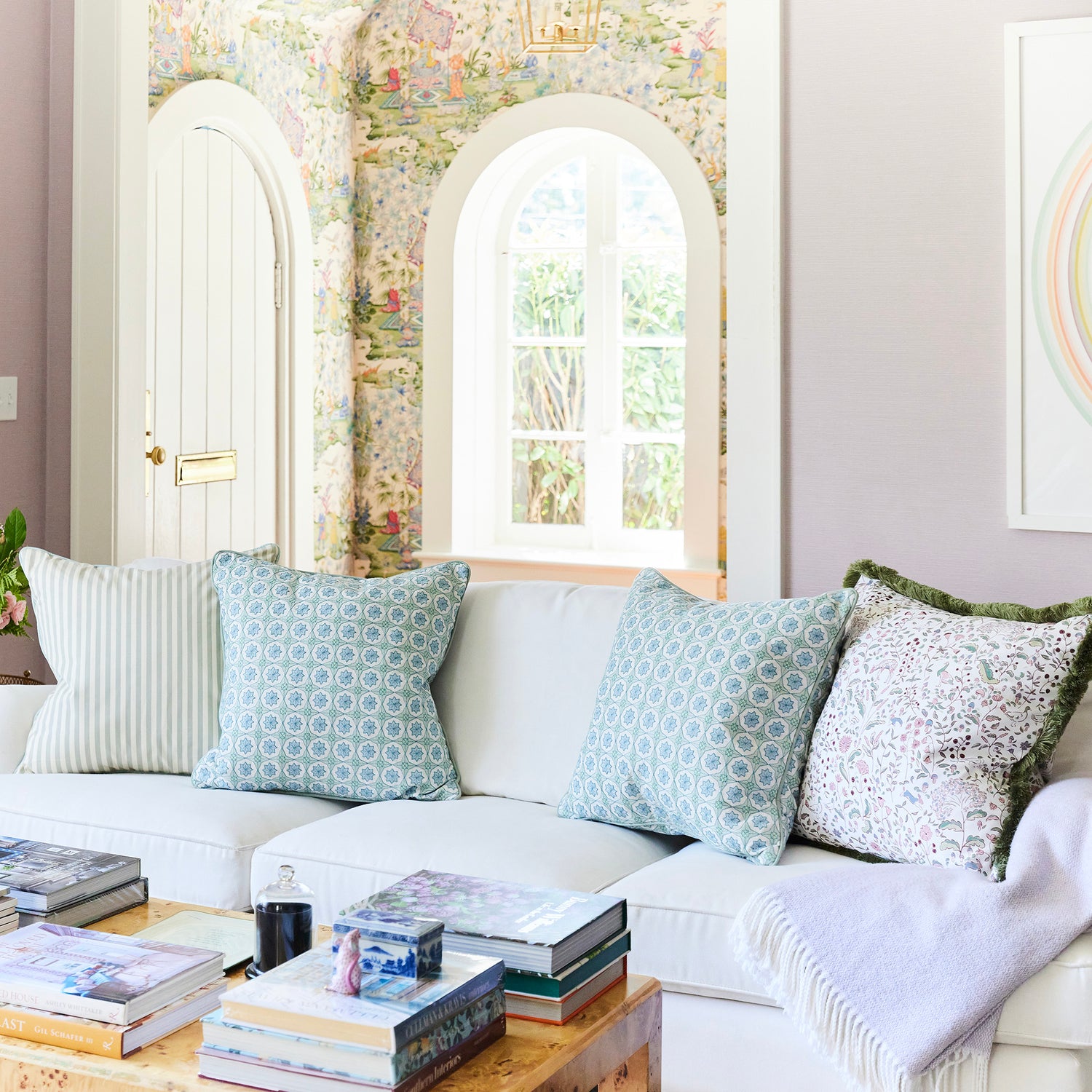 Set of BY Interiors throw pillows in soft blue patterns and floral print with green fringe on a white sofa in bright room