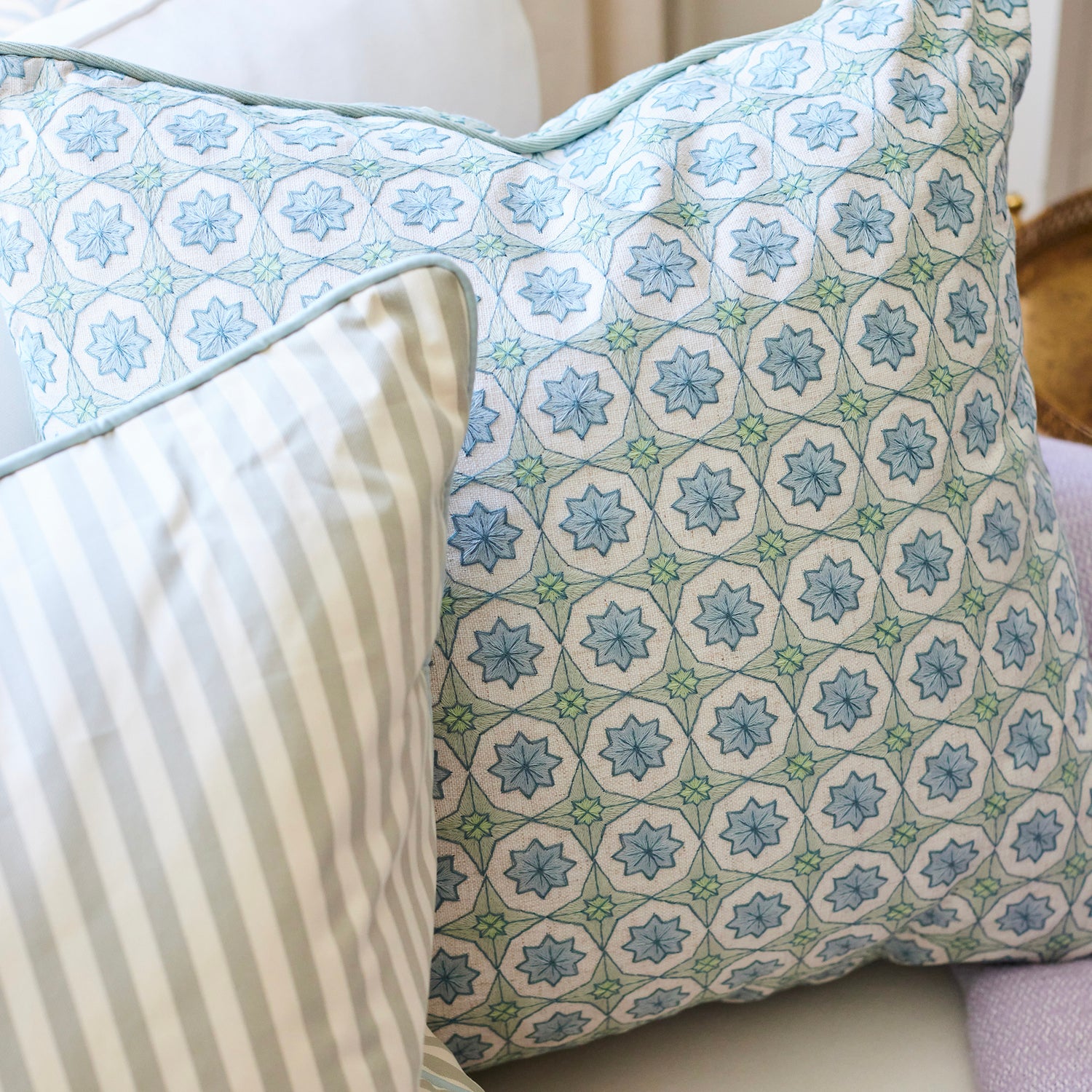 BY Interiors pillows featuring a soft blue geometric floral pattern paired with muted striped fabric for custom decor.