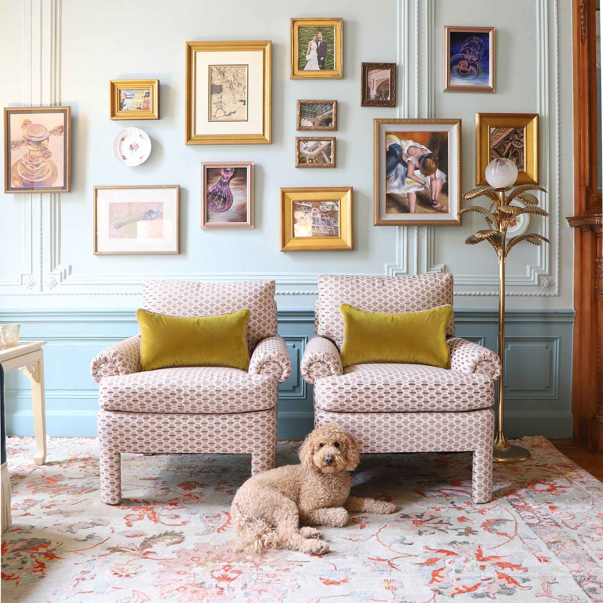 chenille and woven jacquard pink and citron geometric  chairs with golden chartreuse pillows on them in front of a blue wall with artwork hung on the wall
