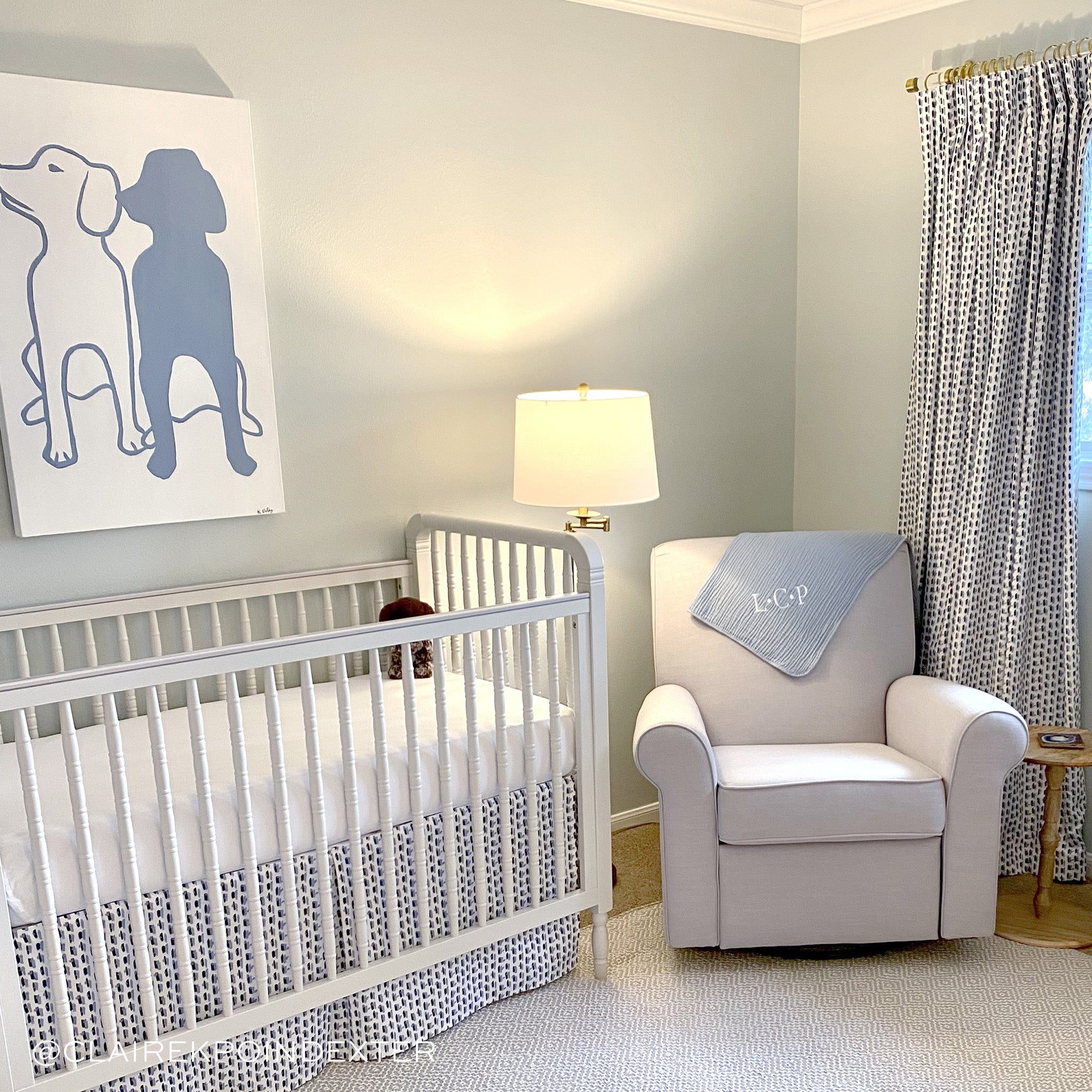 Nursery room styled with Sky and Navy Blue Poppy Printed Curtains matching Sky and Navy Blue Poppy Printed Crib Skirt in between gray couch with monogrammed blanket hanging. Photo taken by Claire K Poindexter