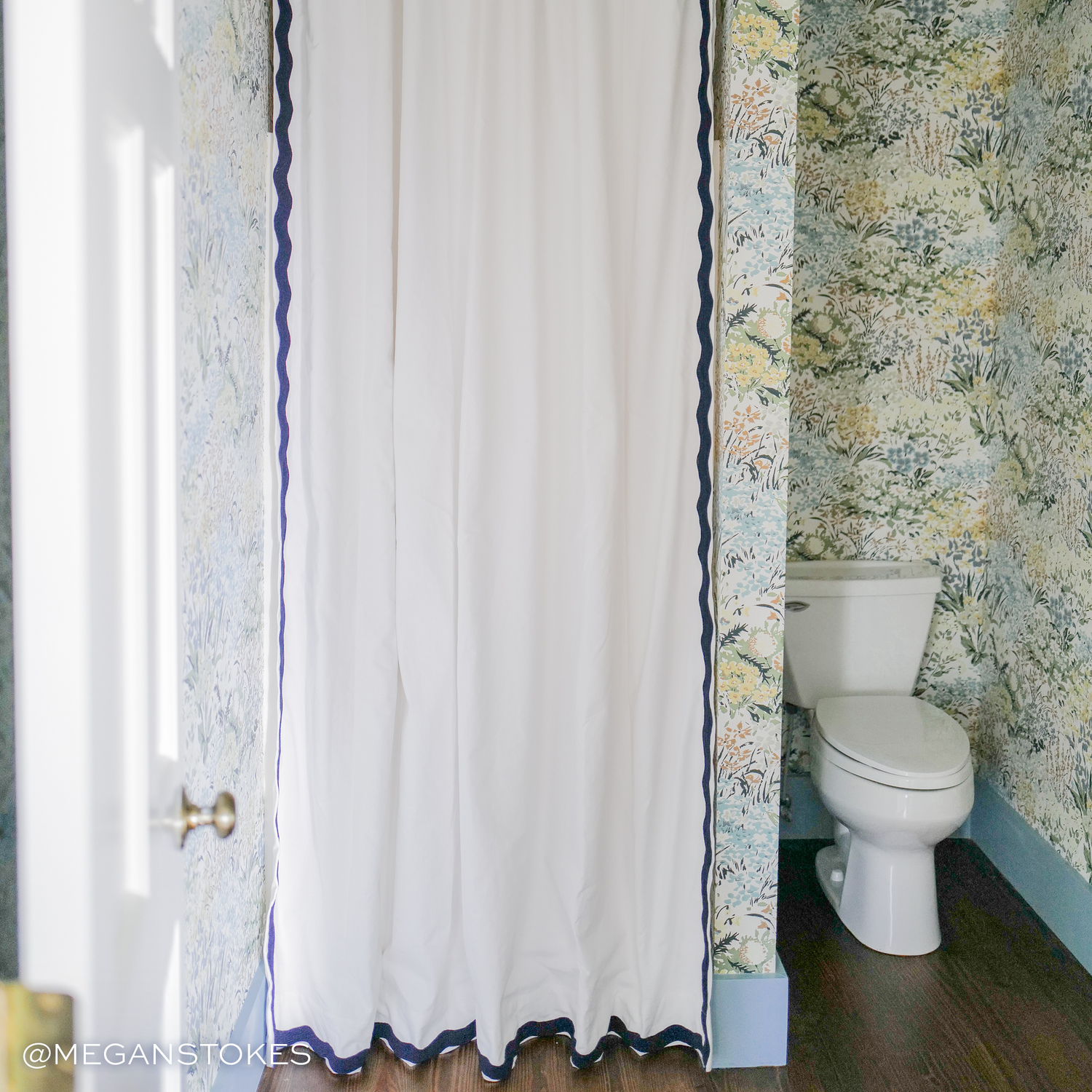 White Cotton shower curtain hanging on rod in bathroom with blue green and yellow floral wallpaper