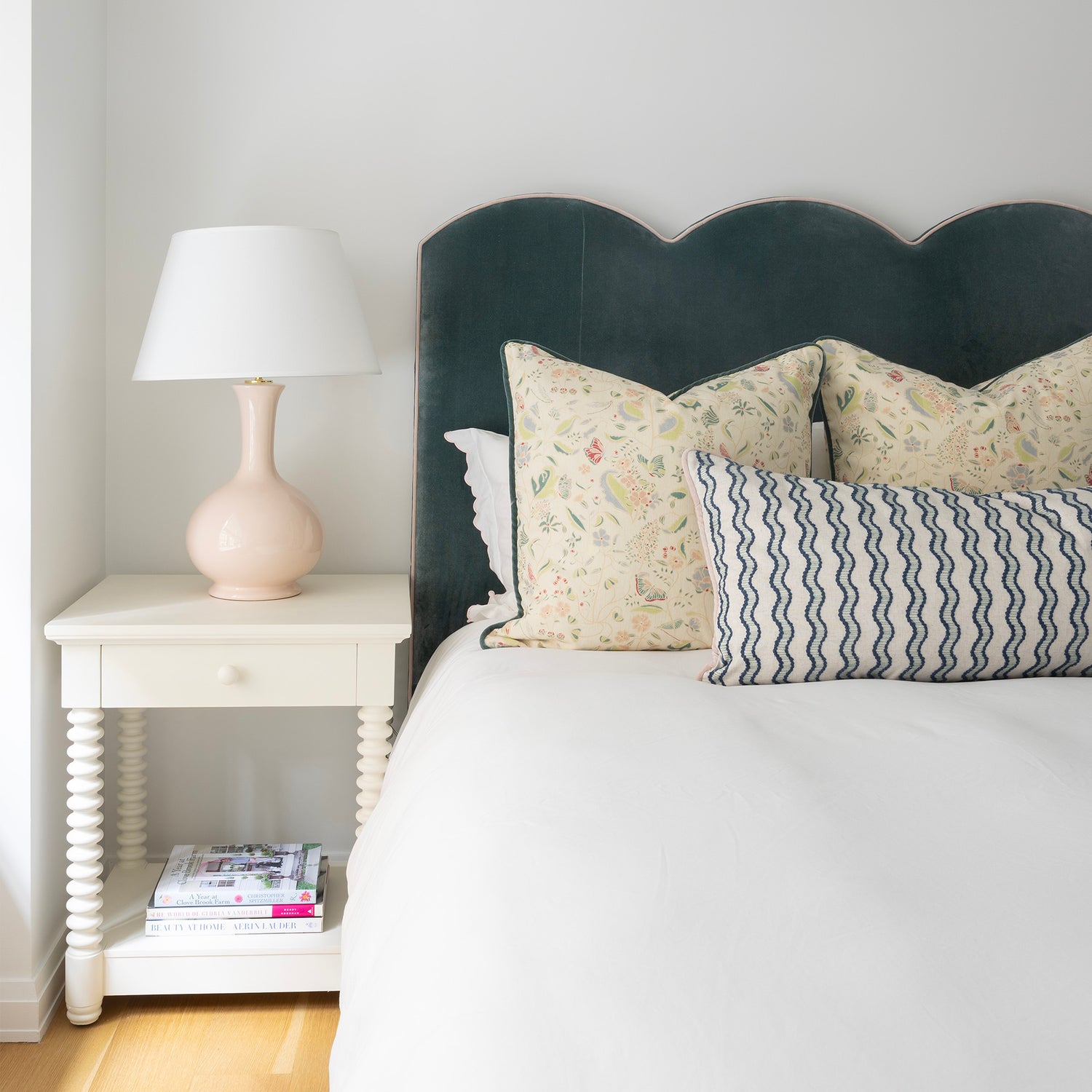 Jennifer Hunter pillow set with floral square pillows and a blue wavy stripe lumbar pillow on a velvet scalloped headboard