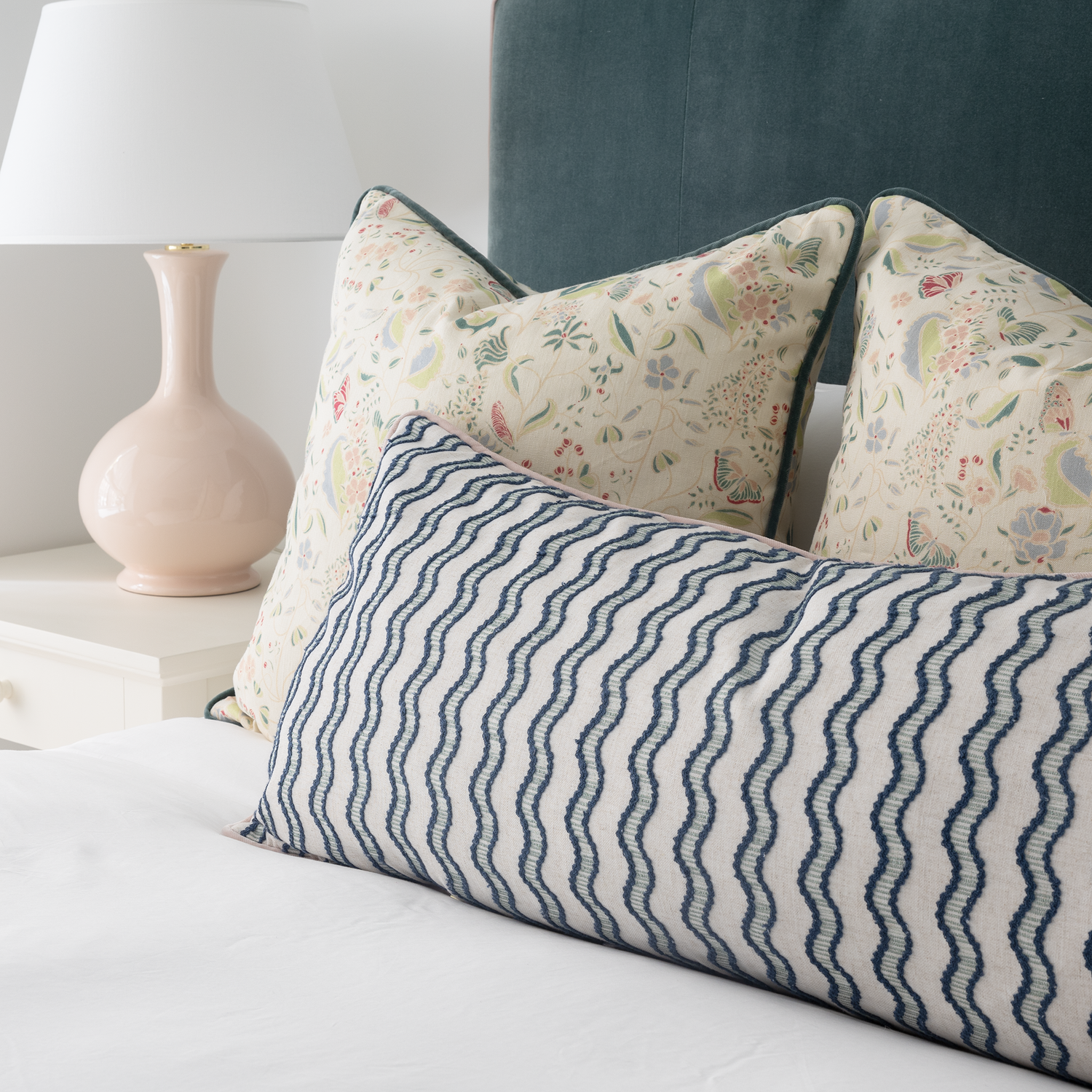 Jennifer Hunter pillow set with floral and bird pattern pillows paired with a blue wavy stripe lumbar pillow on bed