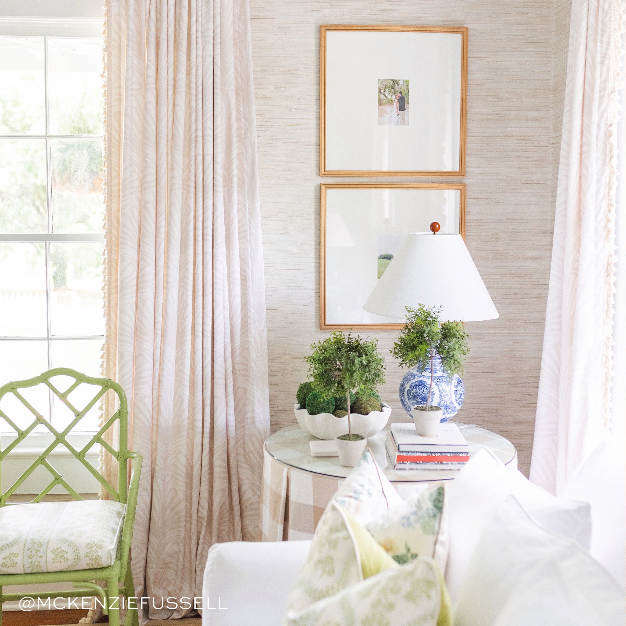 Living room corner styled with Beige Palm printed curtains on illuminated windows next to white couch and circular table with plants, books, and lamp on top. Photo taken by Mckenzie Fussell