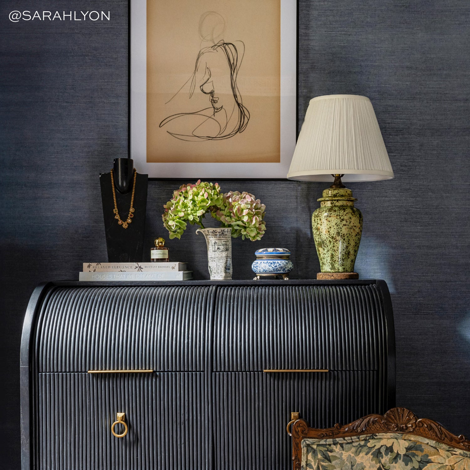 Deep blue-grey textured grasscloth wall covering with curated decorative accents and warm ambient lighting in elegant room setting.