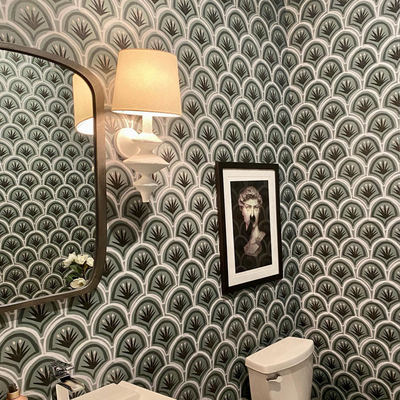 dark green Art Deco Palm pattern wallpaper in a bathroom with a picture of a marble bust hung above the white toilet 