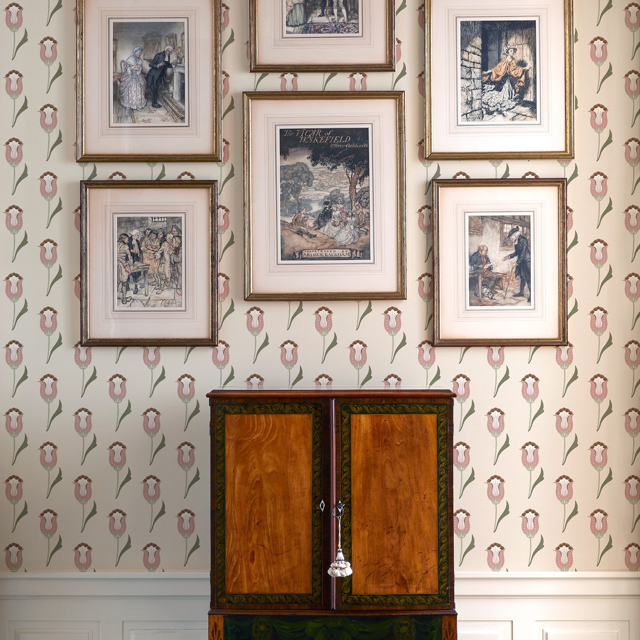 abstract floral pink and green wallpaper on a wall with artwork hung on the wall and a brown cabinet in front