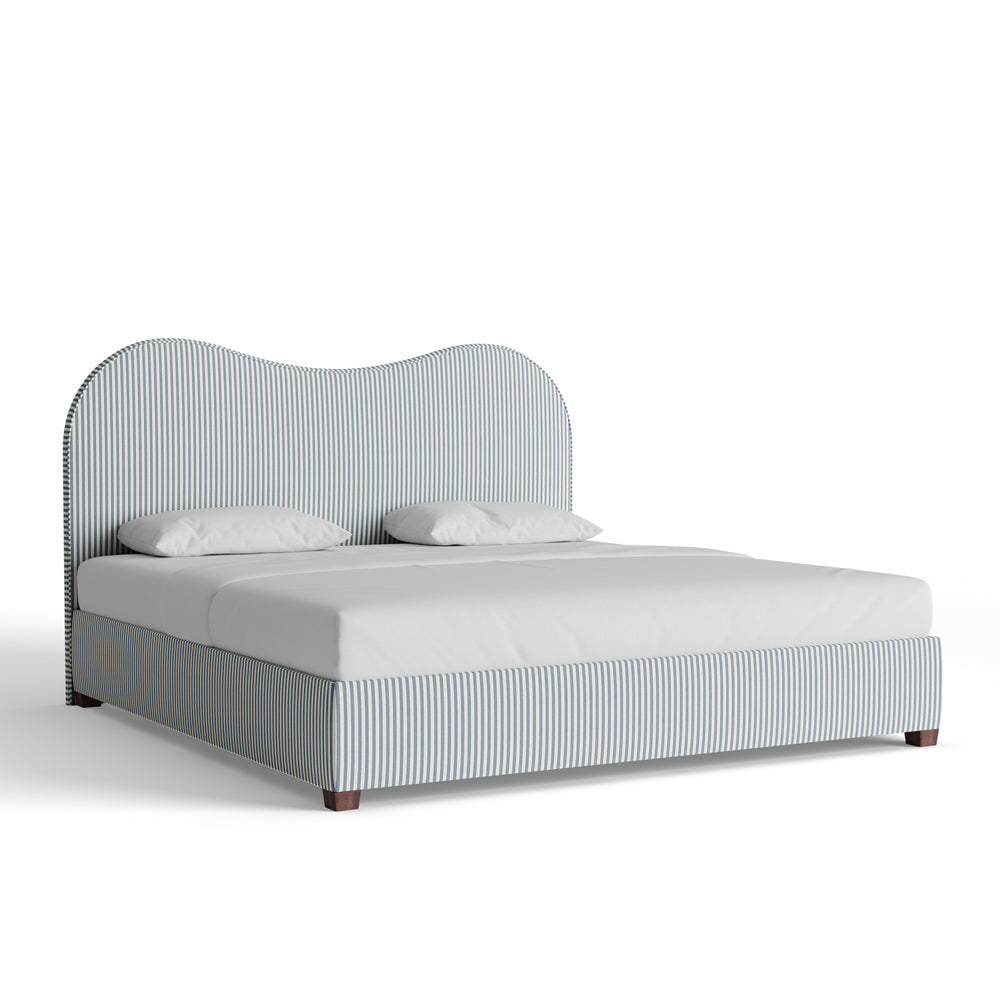 side view of bed on white background with striped fabric and dark wooden feet