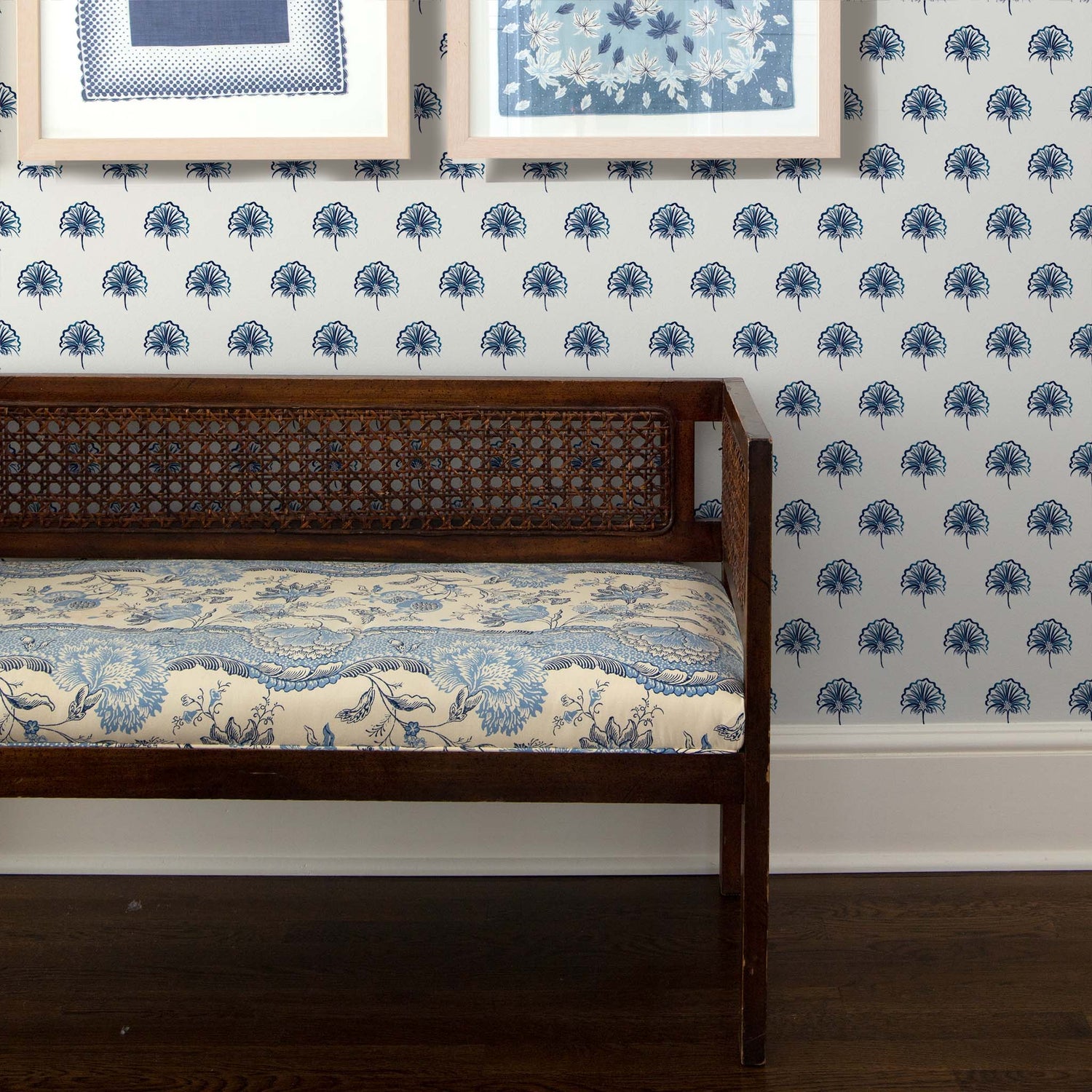 Wooden bench with floral creme printed mattress over Floral Navy Printed Wallpaper with two framed artwork hanging