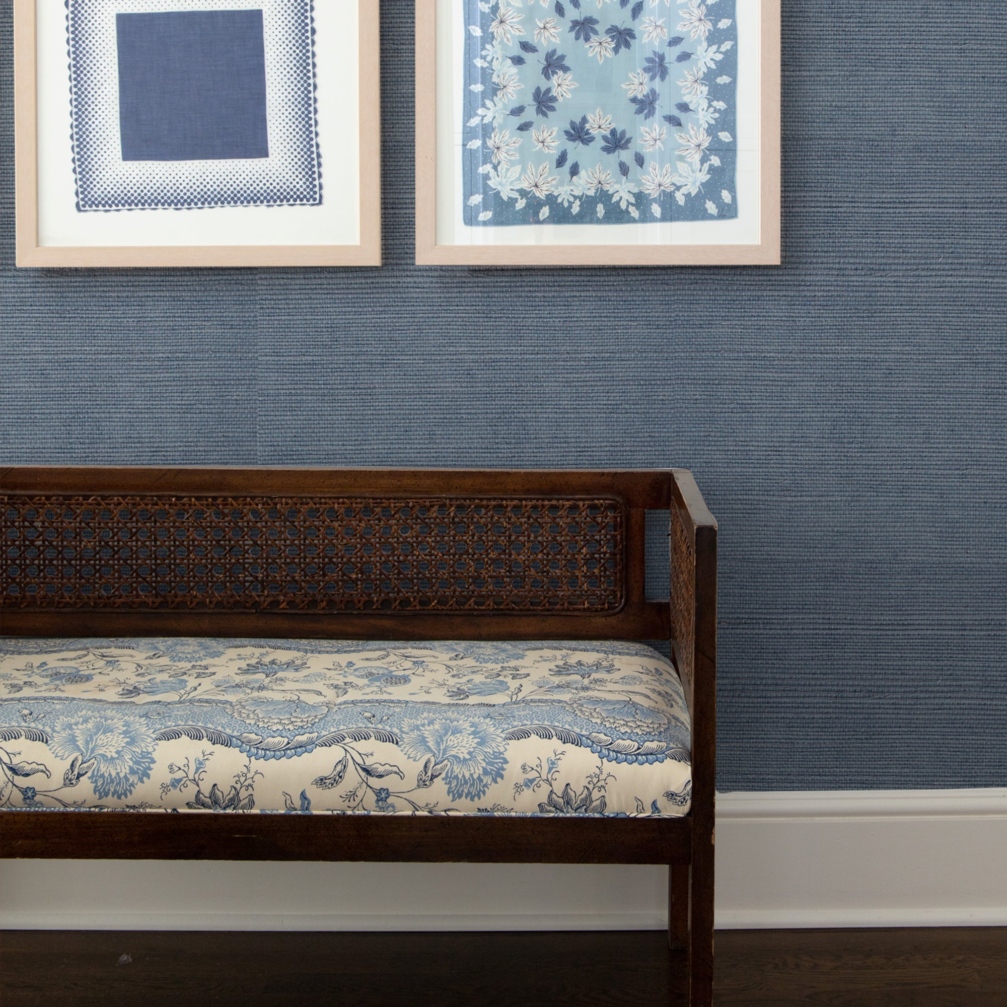wall with Steel Blue Grasscloth Wallpaper and framed images hung on the wall and a brown and blue bench