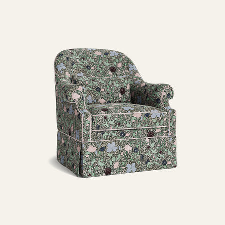 Another view of the green floral armchair with a red piping and wooden legs.