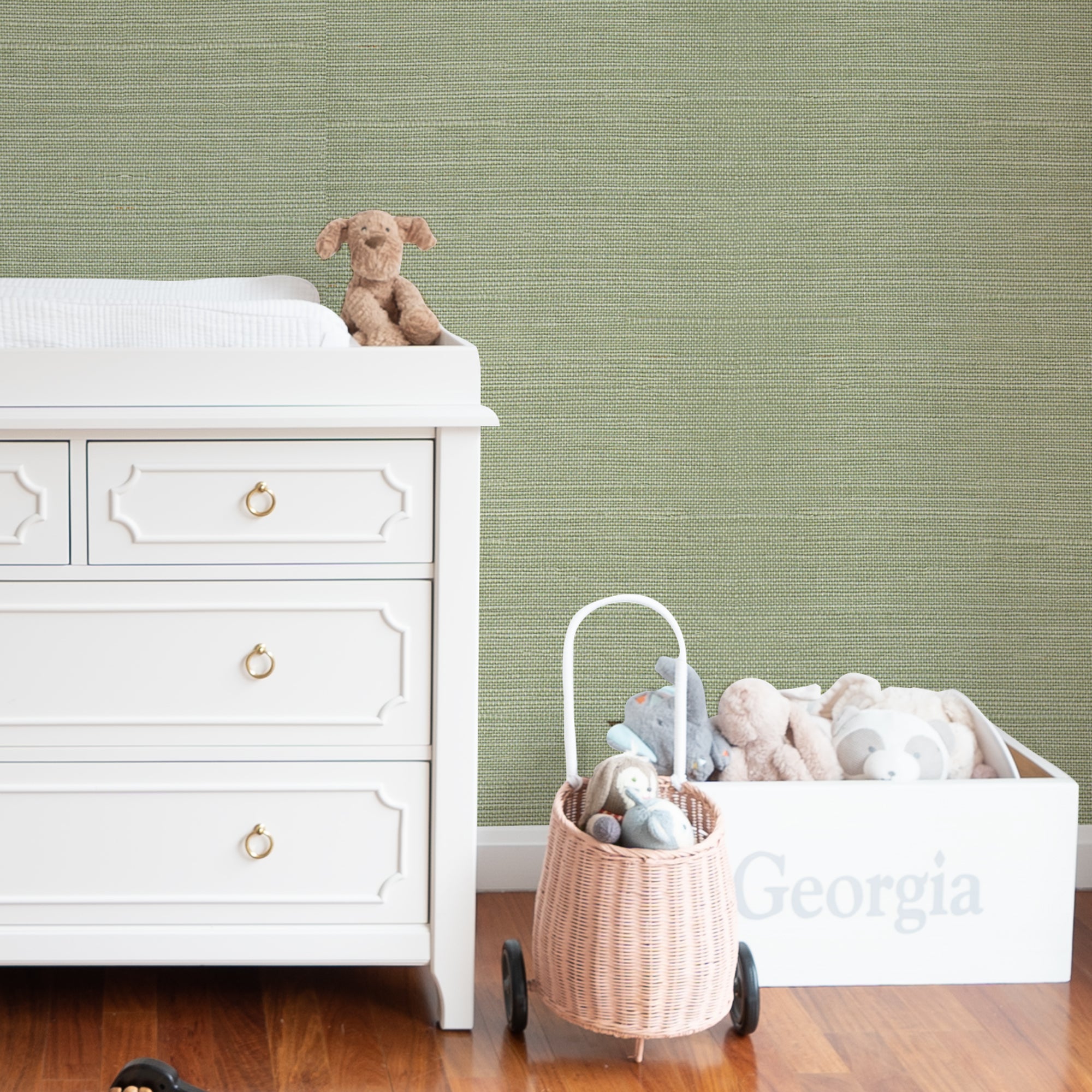 wall with Green Grasscloth Wallpaper and a changing table dresser and stuffed animals
