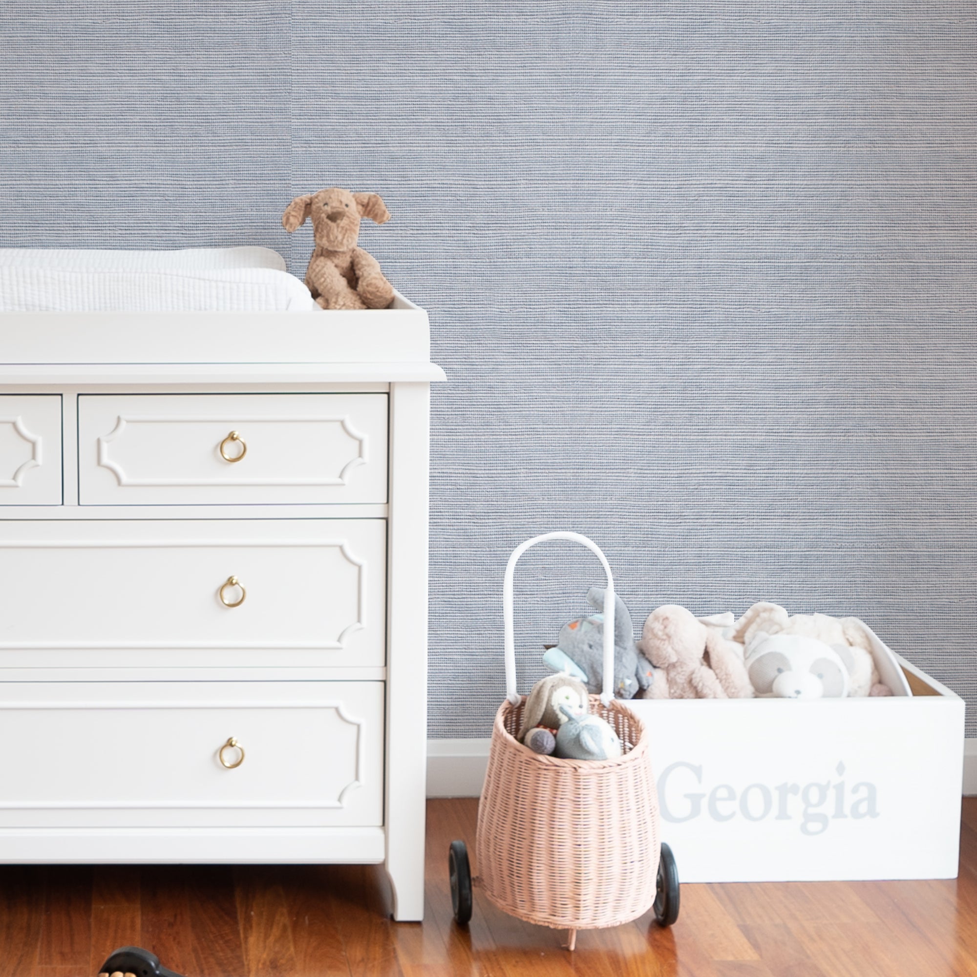 wall with Sky Blue Grasscloth Wallpaper and a changing table dresser and stuffed animals
