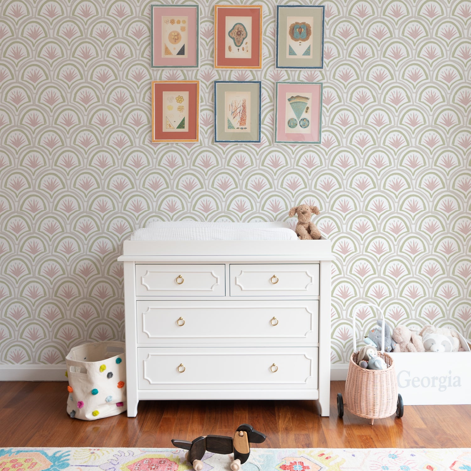 White Changing Table Close-up styled with rose Pink Art Deco Palm printed wallpaper and six framed artworks hung on wall