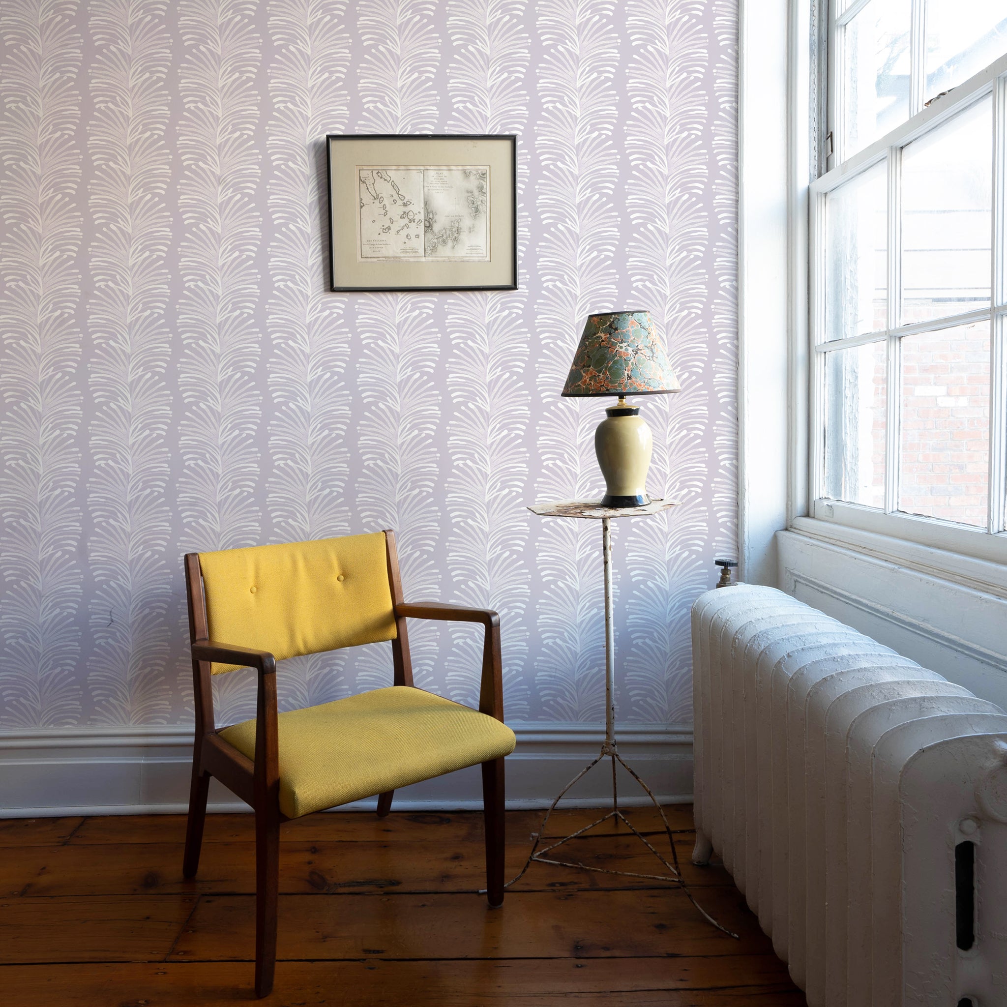 Room corner styled with Lavender Botanical Stripe printed wallpaper with wooden yellow chair in front by green and floral lamp on white circular small table next to window