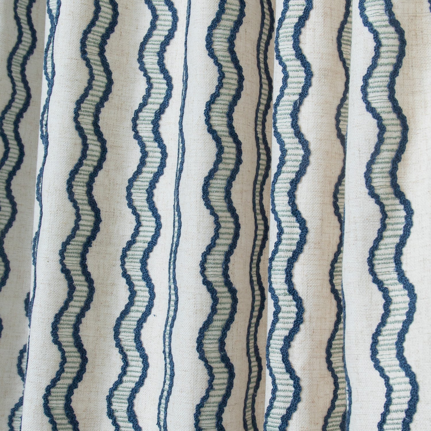close up of embroidered cream curtains with wavy blue lines