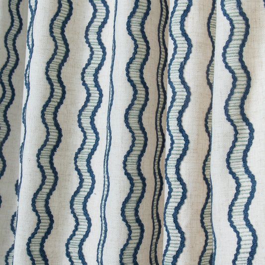 close up of natural white fabric with embroidered peacock blue wavy stripe curtain