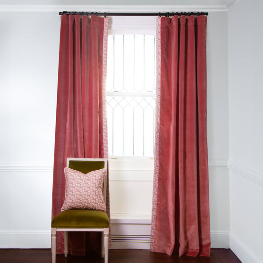 Coral Velvet curtains with Pink Floral fringe on metal rod in front of an illuminated window with Green Moss chair with Pink Floral Pillow on top
