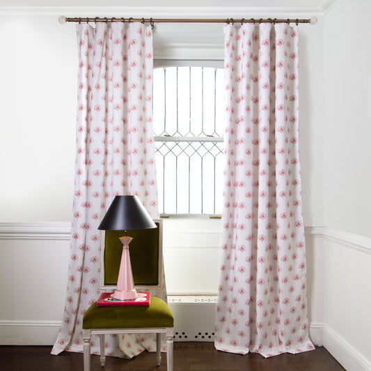 Rose Floral Printed curtains on metal rod in front of an illuminated window with Green Moss chair with pink and black lamp on top of book
