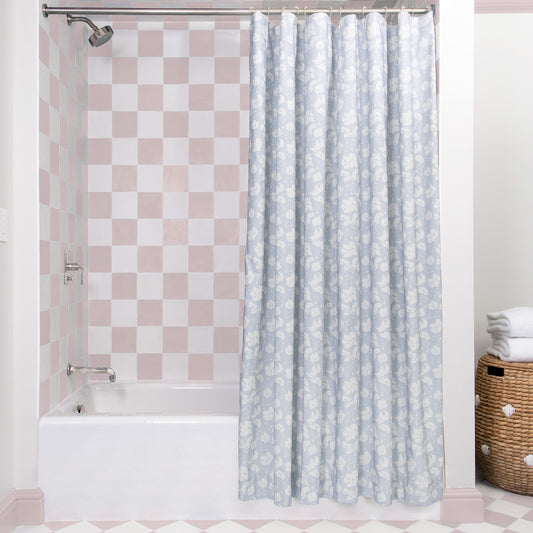 Cornflower Blue Floral shower curtain hanging on rod in front of white tub in bathroom with pink and white tiles