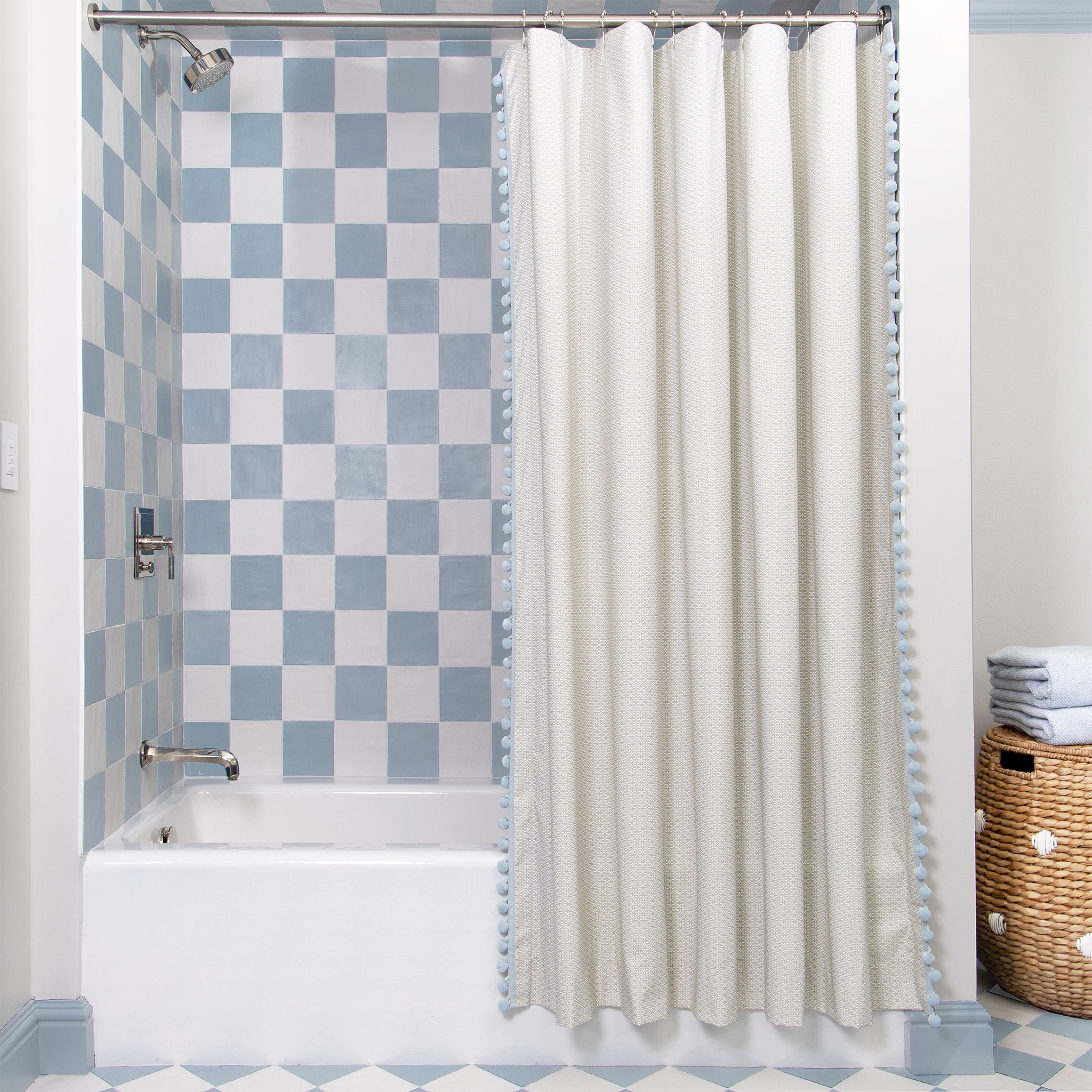 Moss Green Geometric Printed shower curtain hanging on rod in front of white tub in bathroom with blue and white tiles