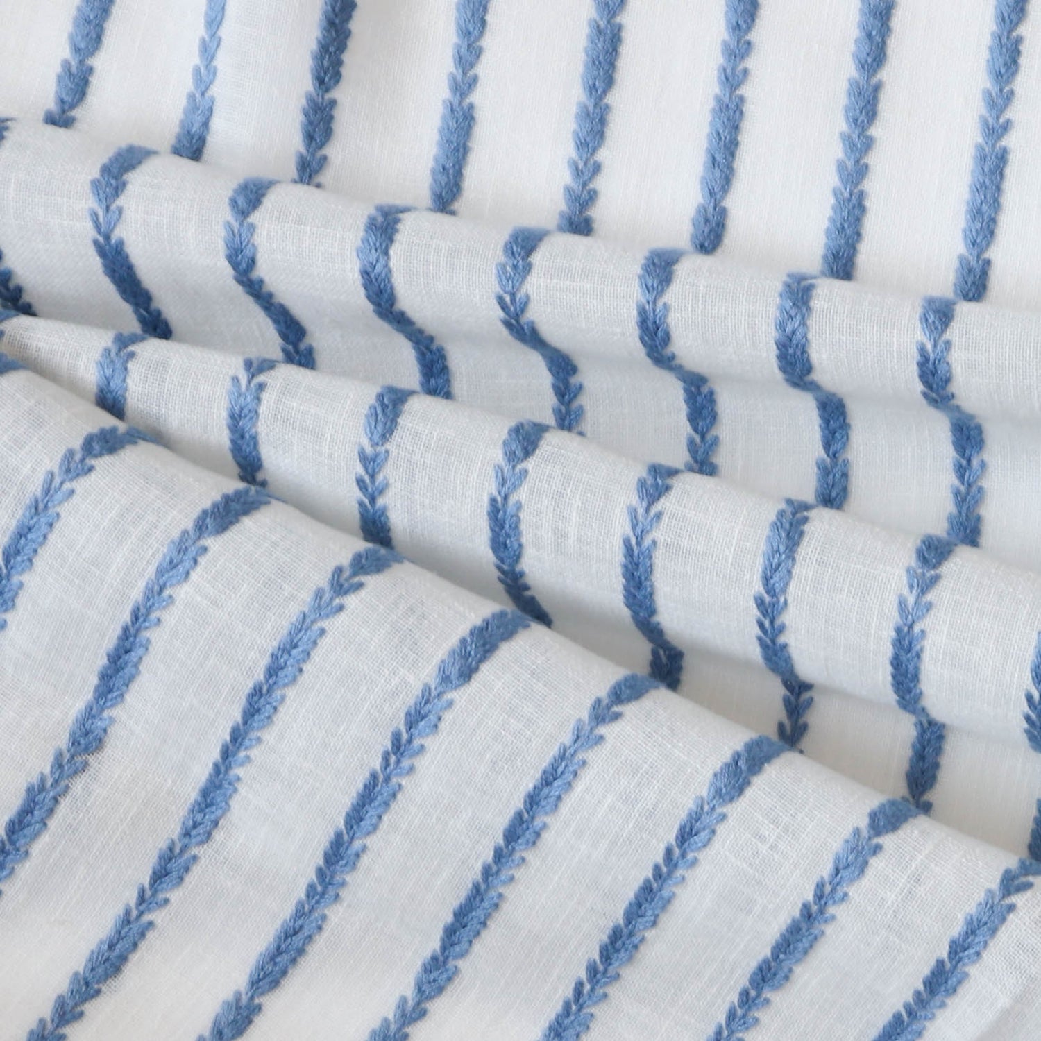 close up of sheer white fabric with cobalt blue embroidered stripes 