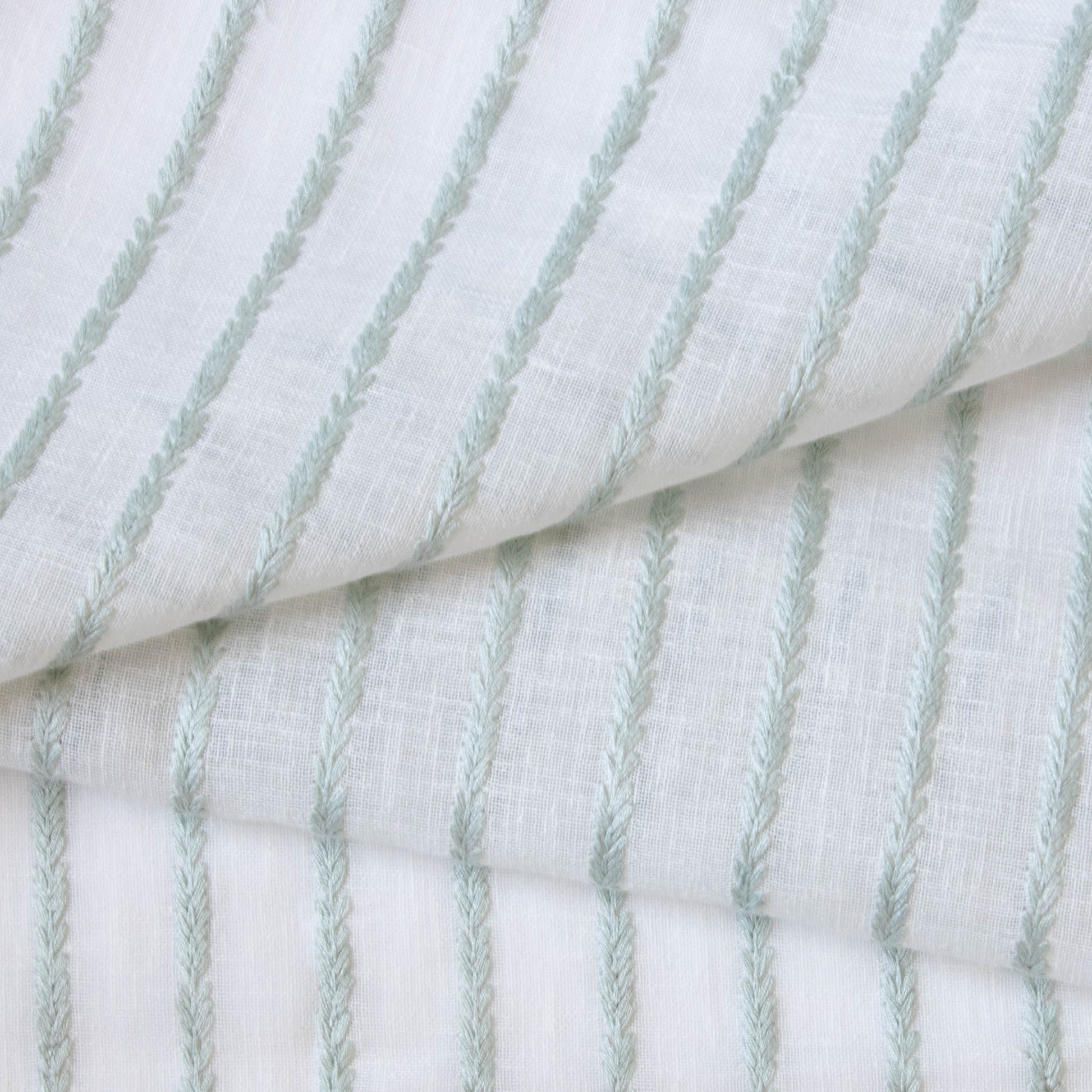 close up of sheer white fabric with mint green embroidered stripes 