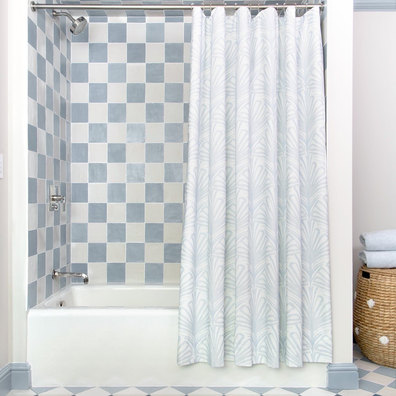 Sky Blue Palm Printed shower curtain hanging on rod in front of white tub in bathroom with blue and white tiles