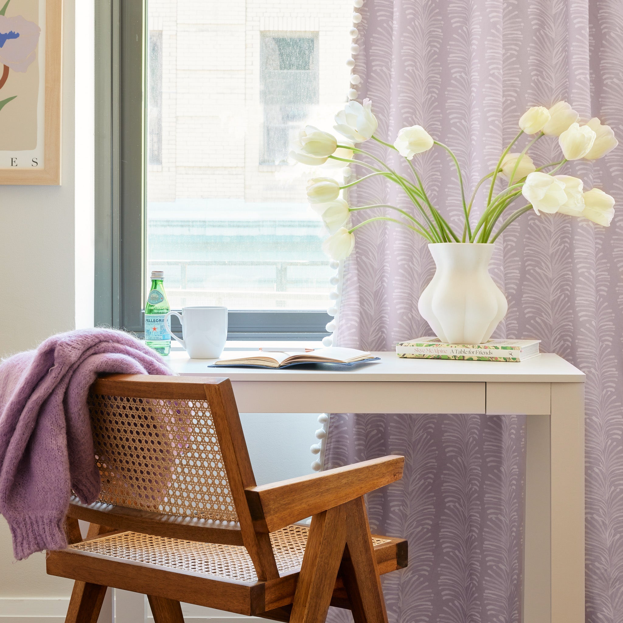 Study Corner styled with wooden chair in front of white table with one open book and one closed book under white vase full of white flowers by Lavender Botanical Stripe Printed Curtain by illuminated window