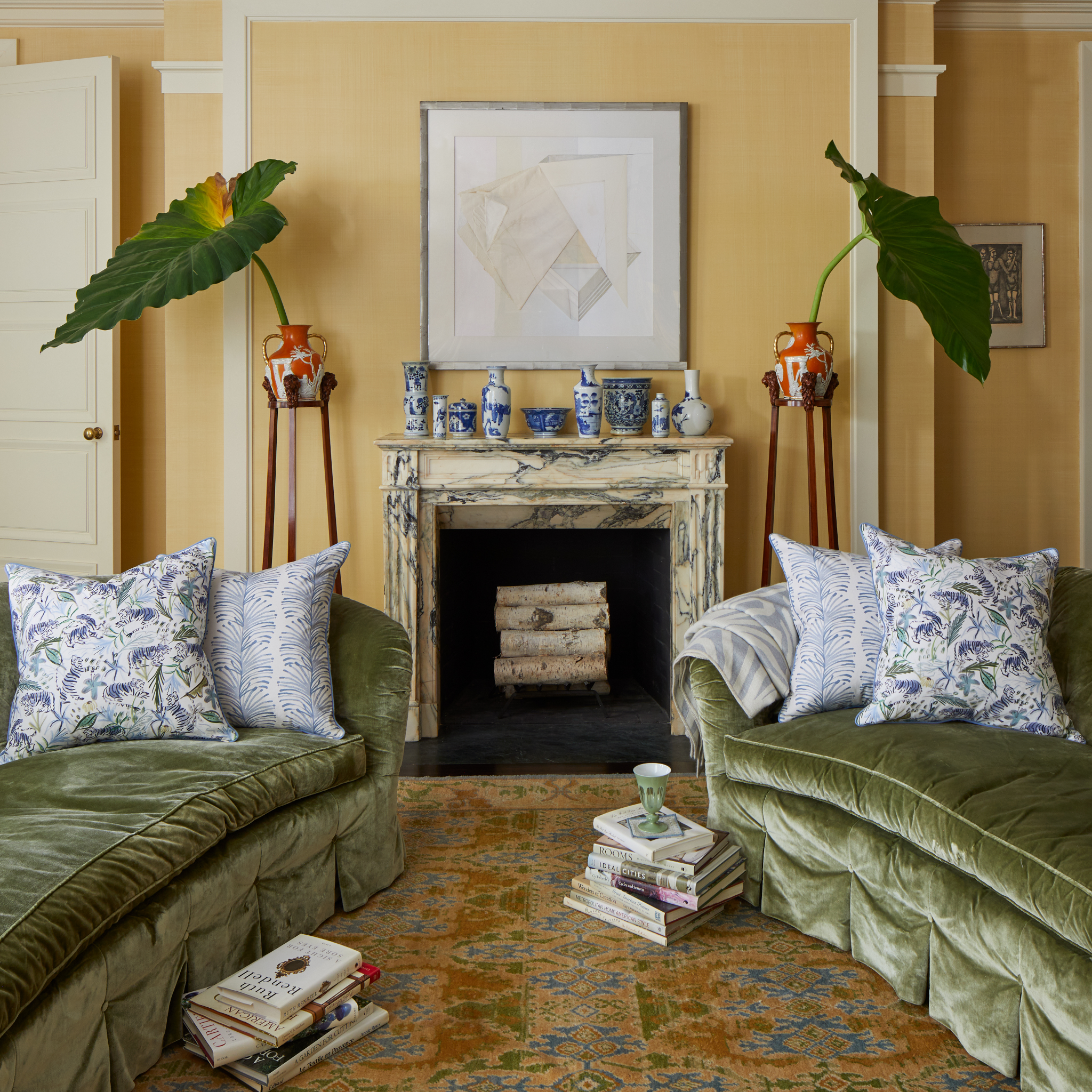 Living room styled with two fern green velvet couches on each side and a Blue With Intricate Tiger Design Printed Pillow and Sky Blue Botanical Stripe Printed Pillow on each couch surrounding two stacks of books on the floor