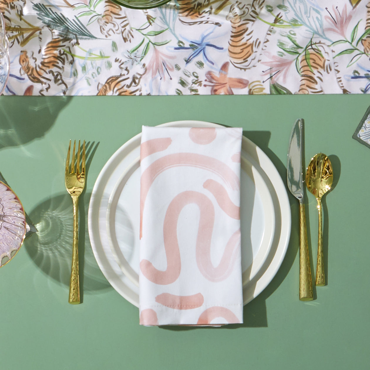 Table Setting Close-Up of White plates with Pink Graphic Printed Napkin and gold silverware by Pink Chinoiserie Tiger Printed runner 