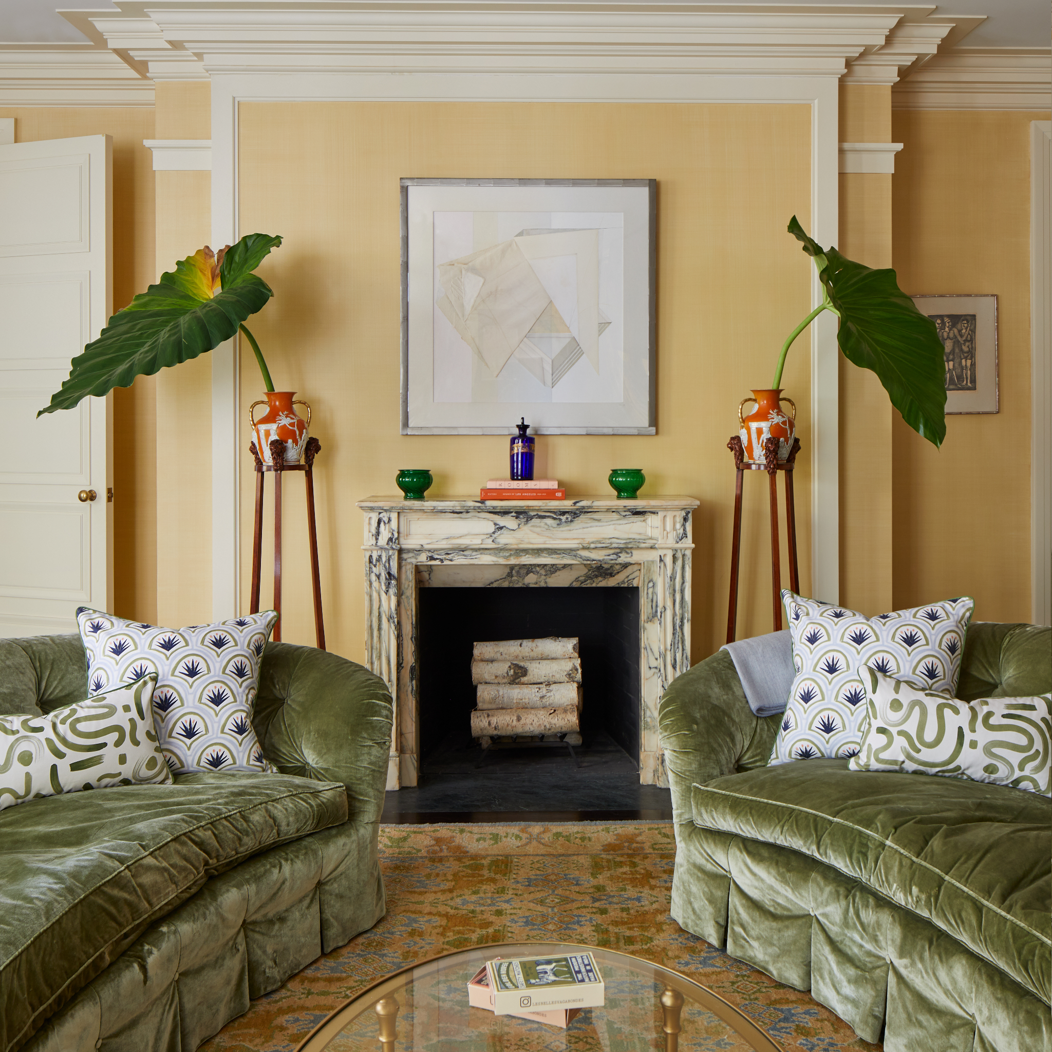 Living room styled with two fern green velvet couches facing each other styled with one Art Deco Palm Pattern Printed Pillow and one Moss Green Printed Lumbar on each in front of a fireplace