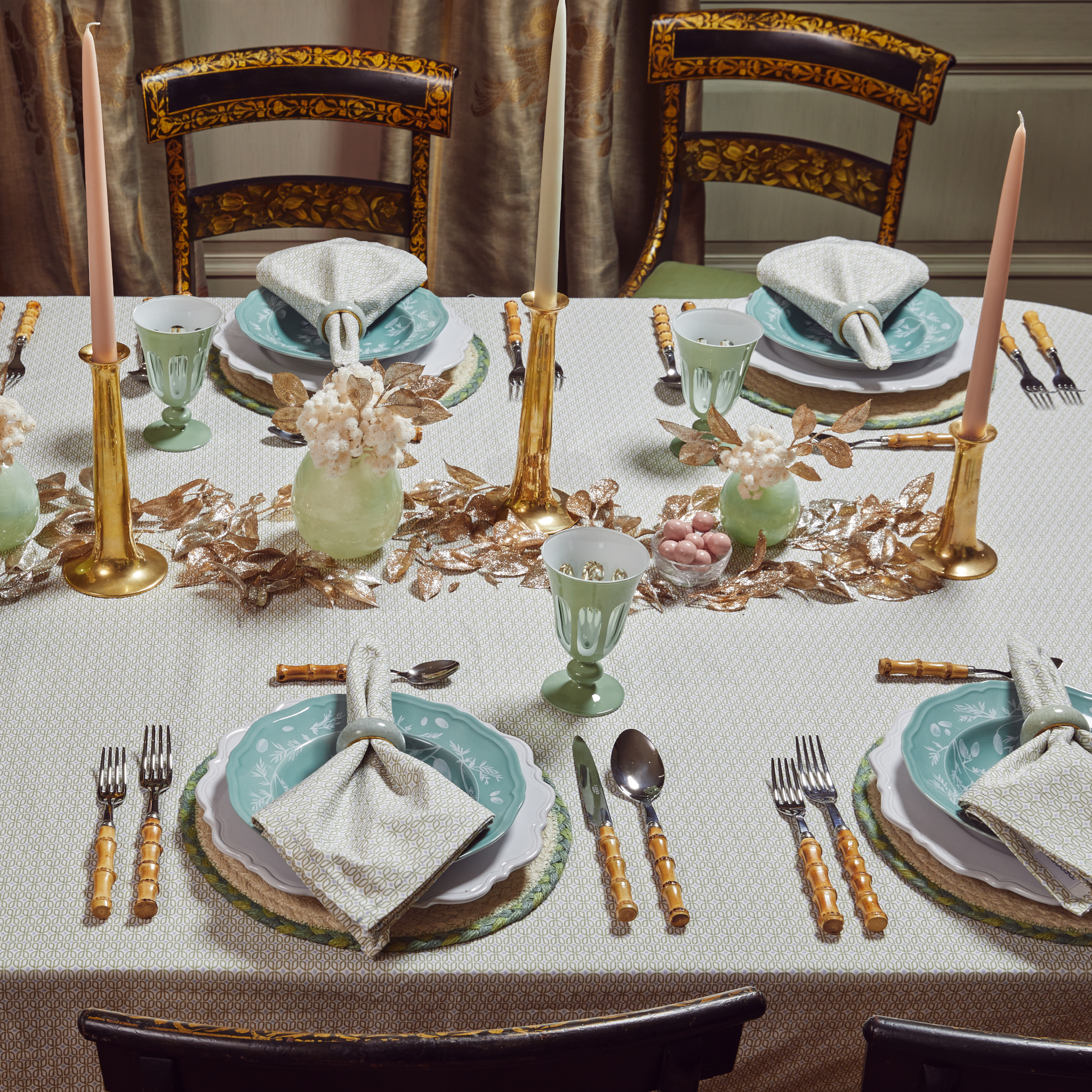 Close-up of Christmas Table Set up styled with a Moss Green Geometric Printed Tablecloth and napkins with three tall candles in the middle