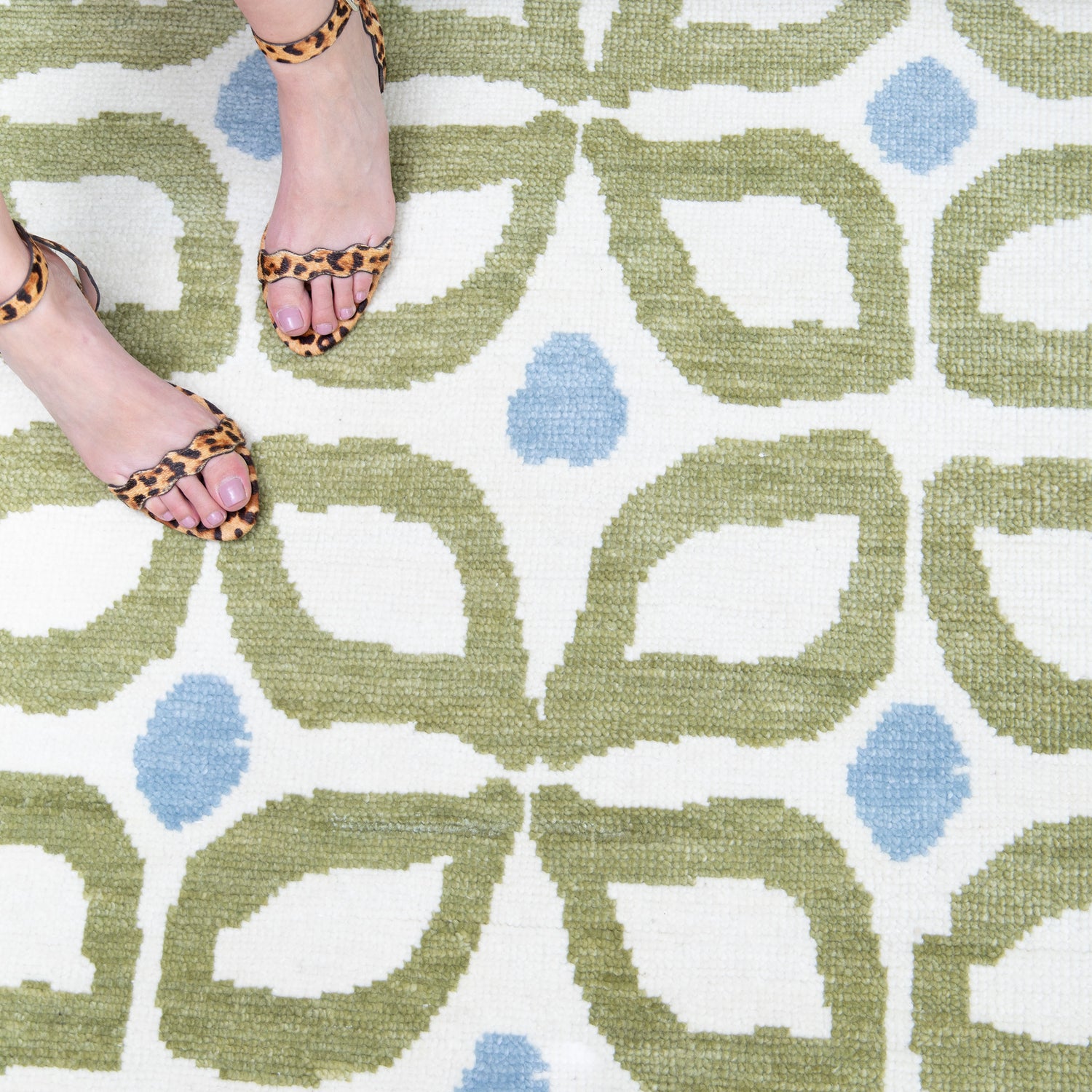 Moss Green Geometric Printed Rug Close-up with cheetah print heels on woman's feet in the upper left corner