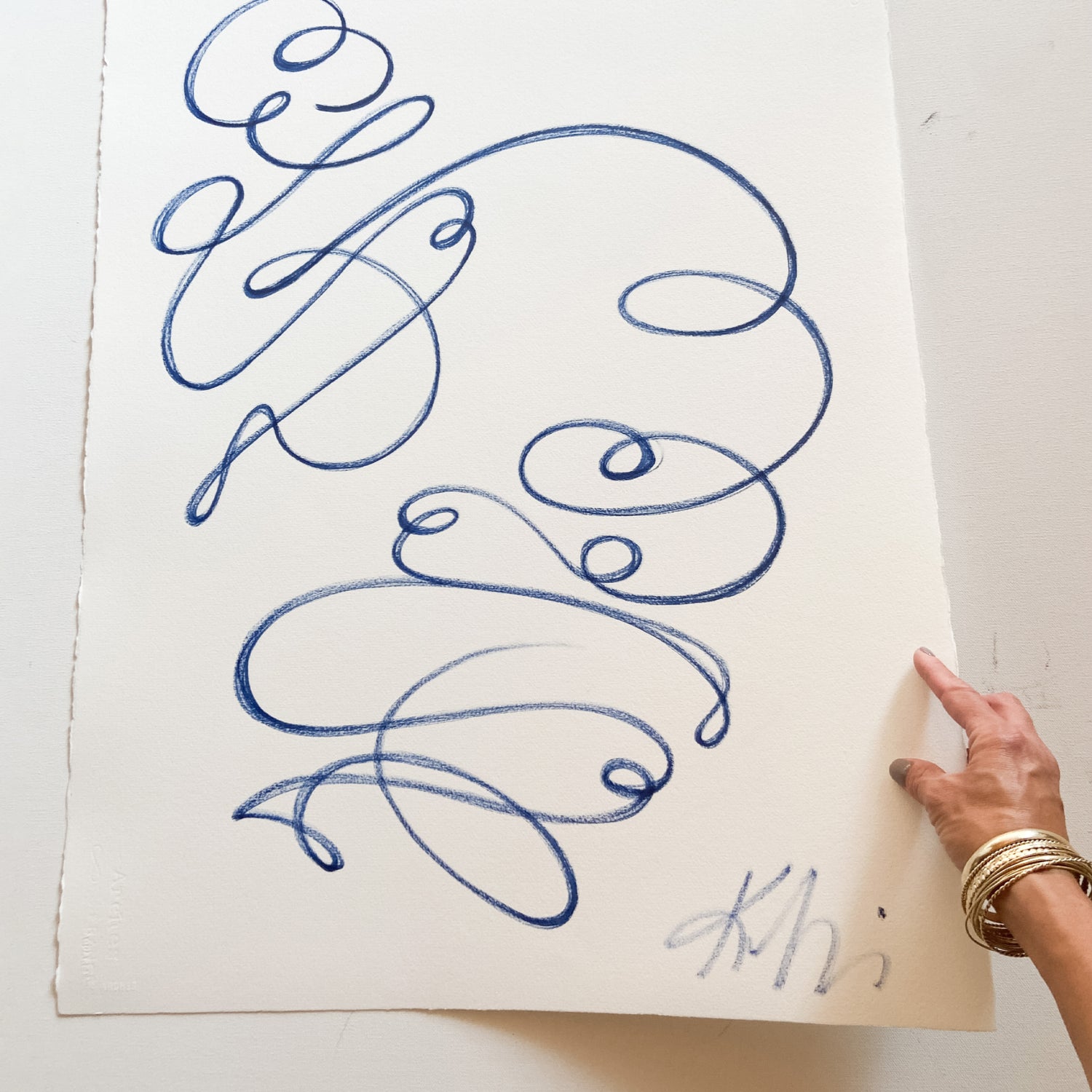 Powder Blue Abstract Design on Paper being held with one hand with gold bracelets