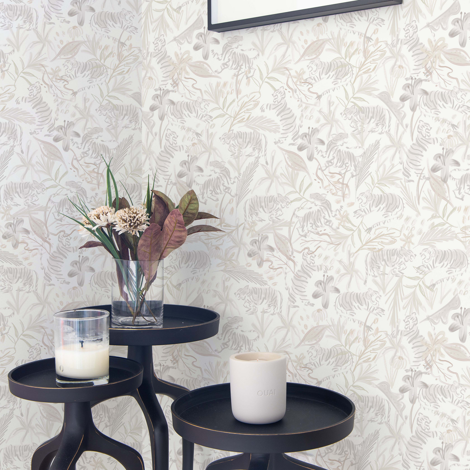 Corner styled with Beige Chinoiserie Tiger Printed Wallpaper next to three dark decorative tables holding two candles and plants in clear vase 