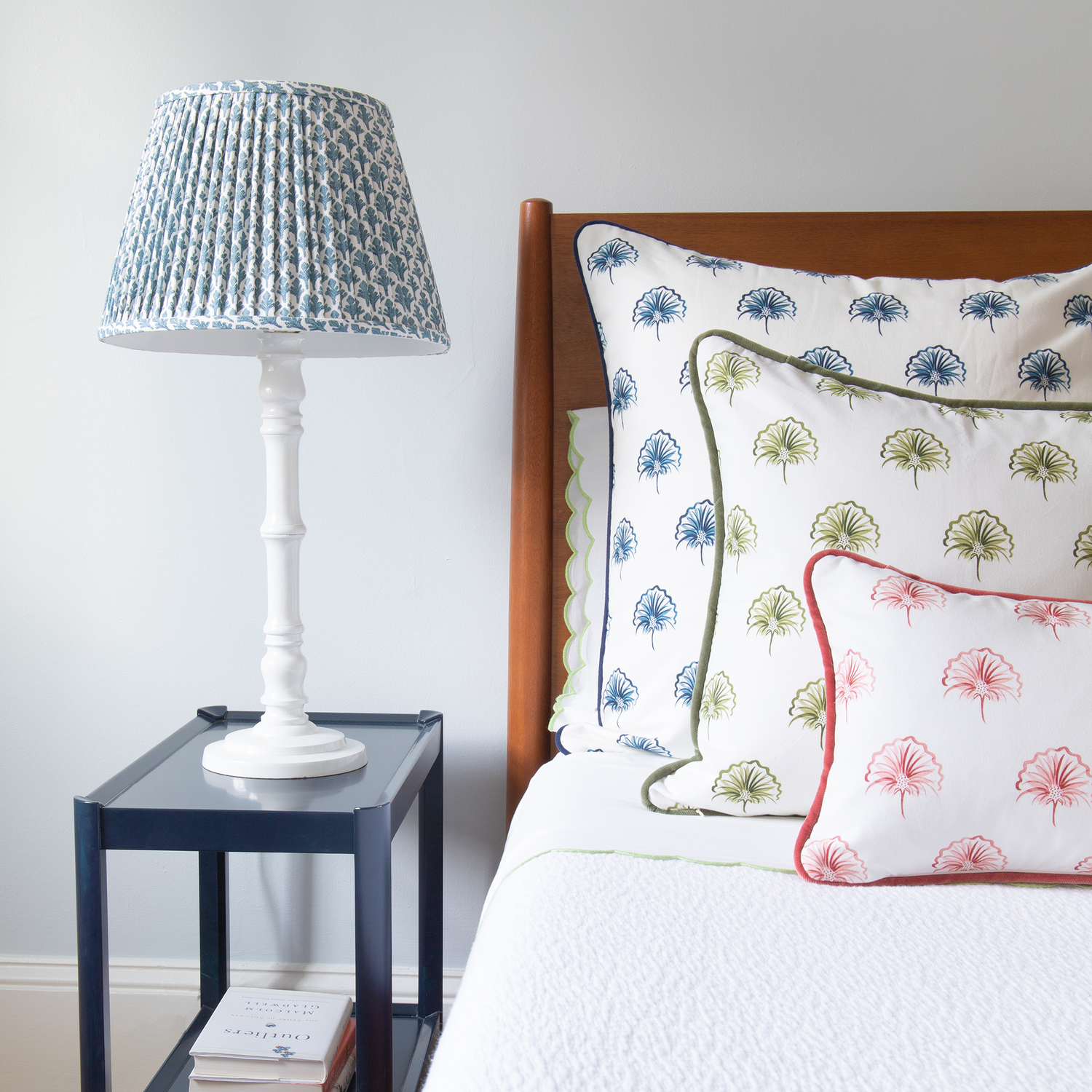 Bed Close-up styled with Floral Navy Printed Pillow, Floral Green Printed Pillow, and Rose Floral Printed Pillow next to navy blue nightstand with white lamp on top