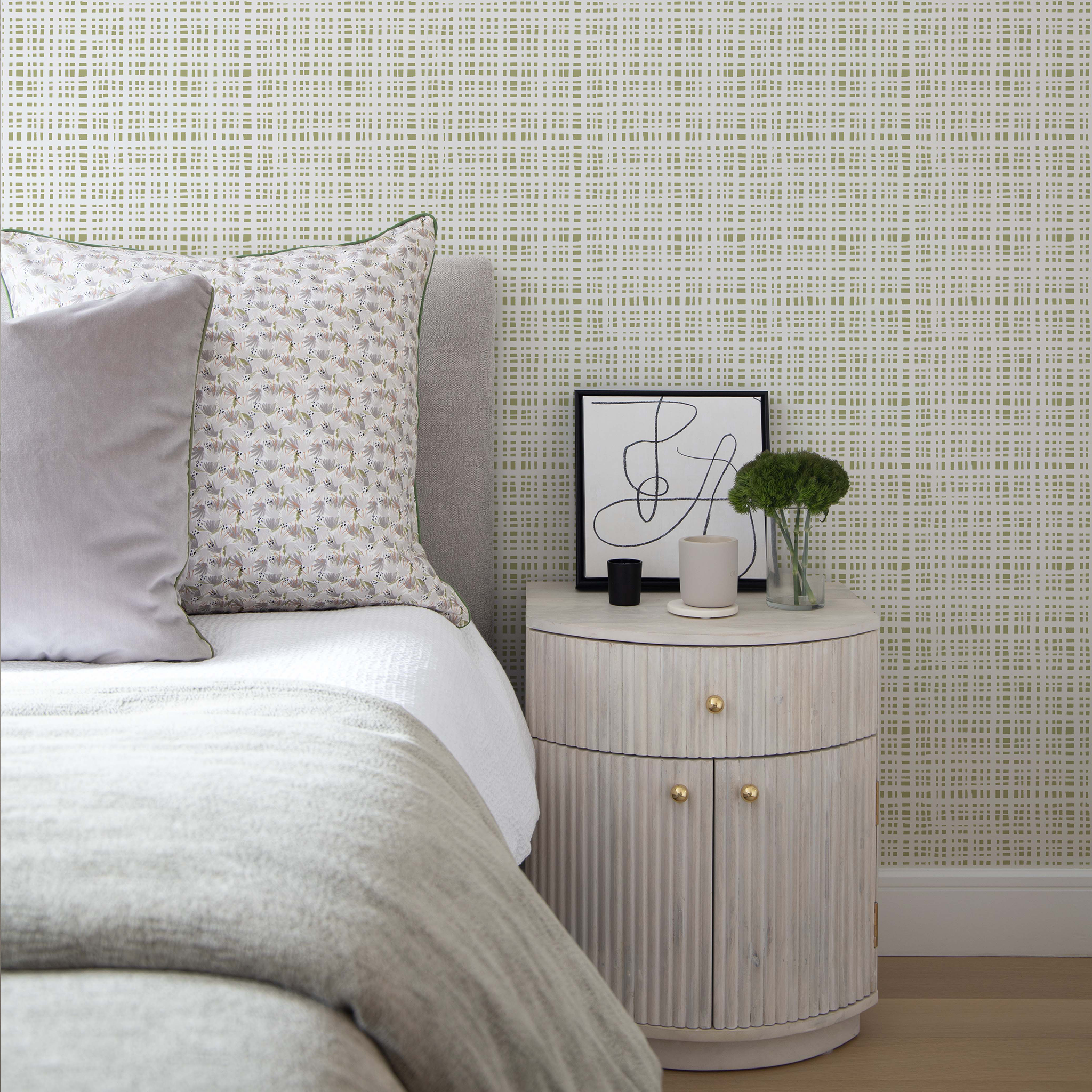 Cream bedroom night stand close-up styled with green moss gingham printed wallpaper and grey floral printed pillow on white bed with grey velvet pillow on front
