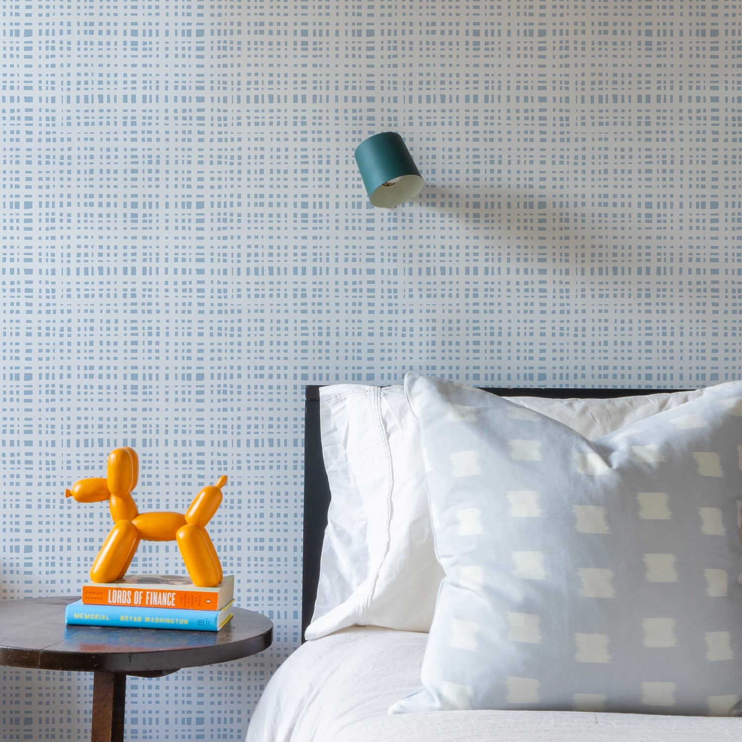 Bedroom Close-Up with two stacked books and orange decoration on top of wooden nightstand next to white bed styled with a Sky Blue Pattern Printed Pillow and Sky Blue Gingham Printed Wallpaper