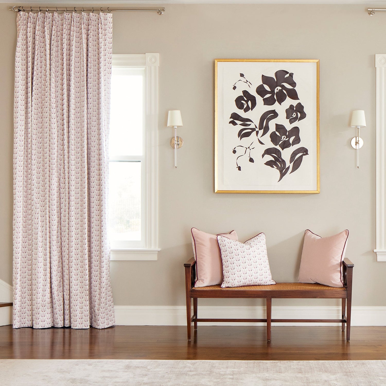 Room corner styled with Pink & Burgundy Drop Repeat Floral Printed Curtains next to bench with two Pink Velvet Pillows and one Pink & Burgundy Drop Repeat Floral Printed Pillow below a floral artwork
