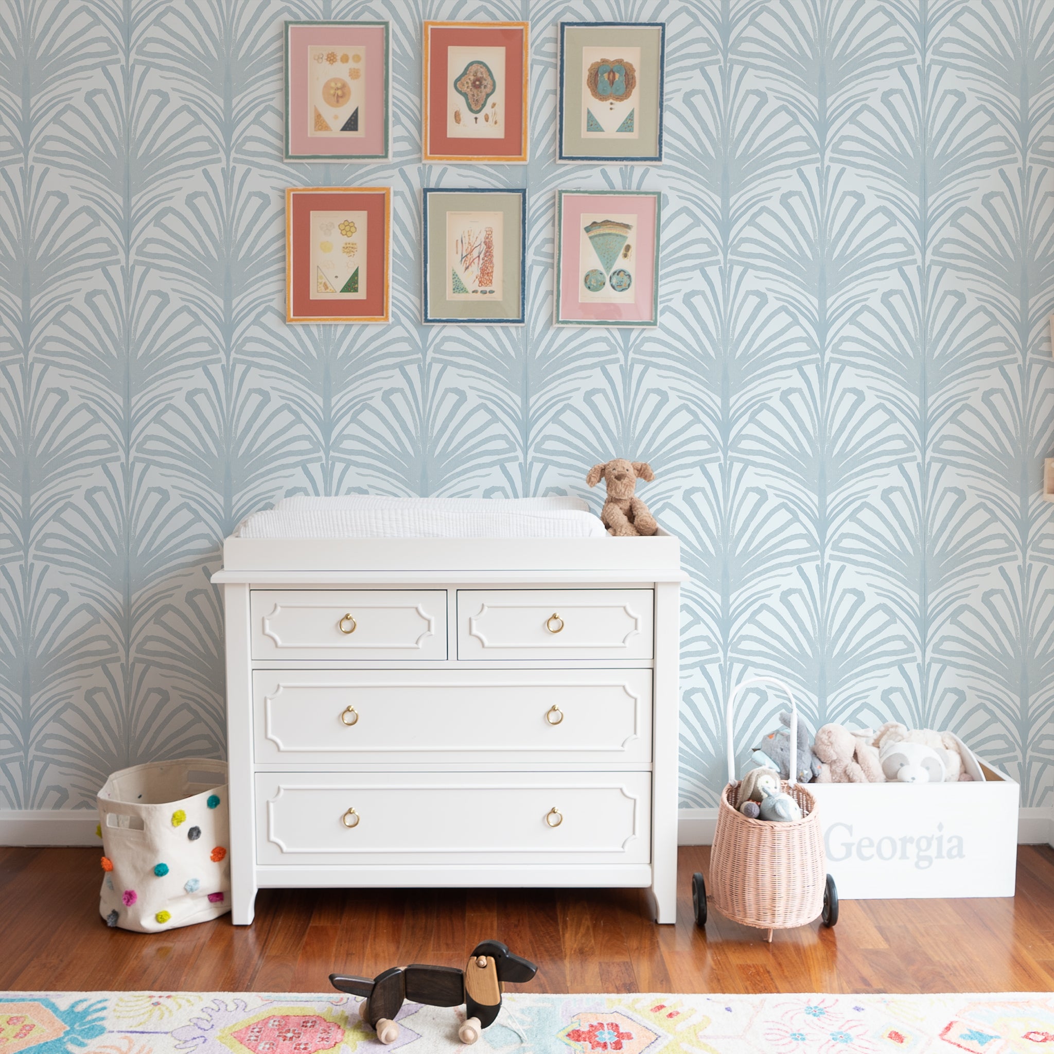 White Changing Table Close-up styled with Sky Blue Palm printed wallpaper and six framed artworks hung on wall