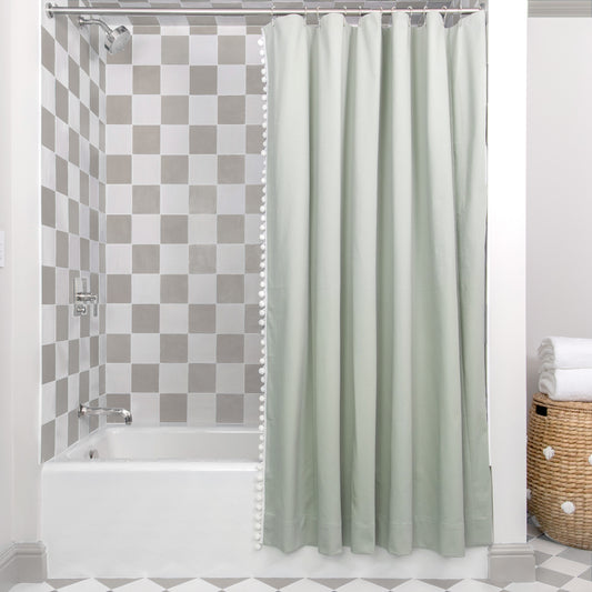 Sage Green shower curtain hanging on rod in front of white tub in bathroom with light brown and white tiles