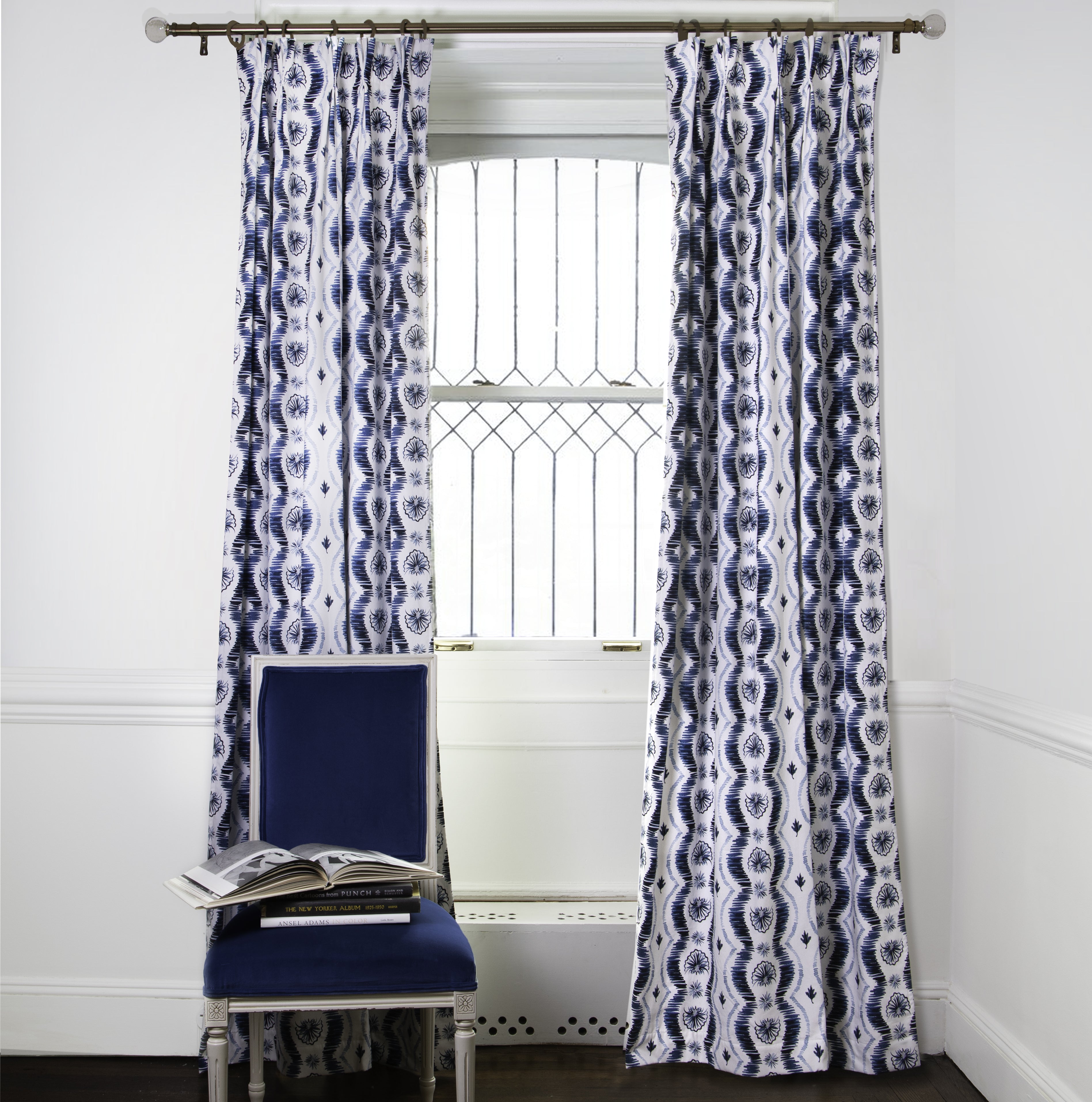 Blue Itak Striped Printed Custom Curtains on metal rod in front of an illuminated window with navy chair in front stacked with books