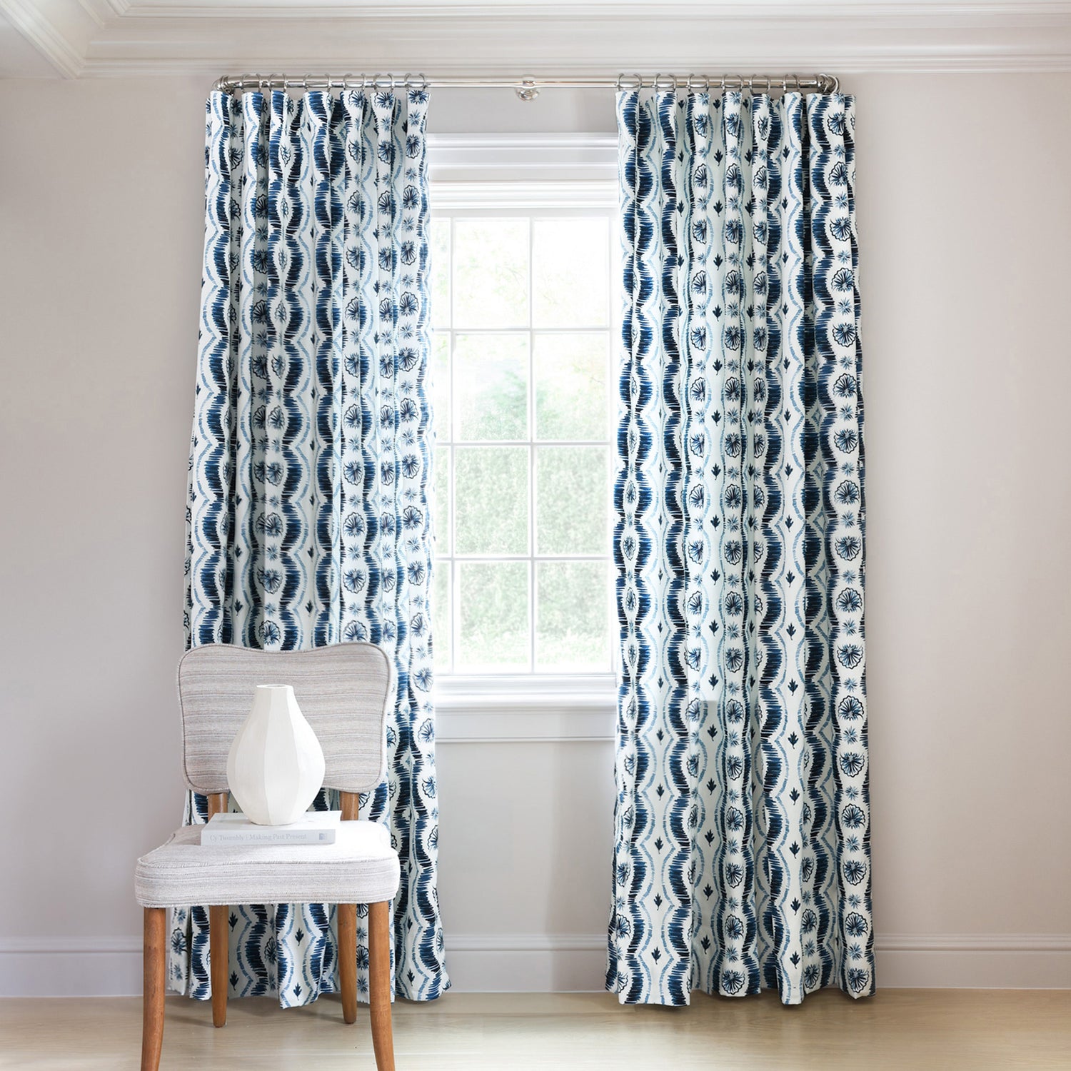 Blue Itak Striped Printed Custom Curtains on metal rod in front of an illuminated window with navy chair in front stacked with books