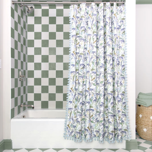 Green Tiger shower curtain hanging on rod in front of white tub in bathroom with green and white tiles