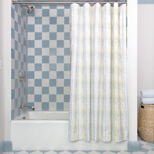 Blue & Green Striped Printed Shower Curtain hanging on rod in front of white tub in bathroom with blue and white tiles