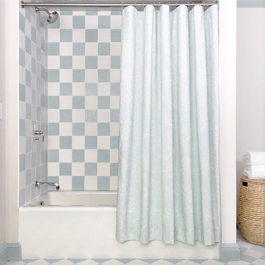 Powder Blue Abstract Printed shower curtain hanging on rod in front of white tub in bathroom with blue and white tiles