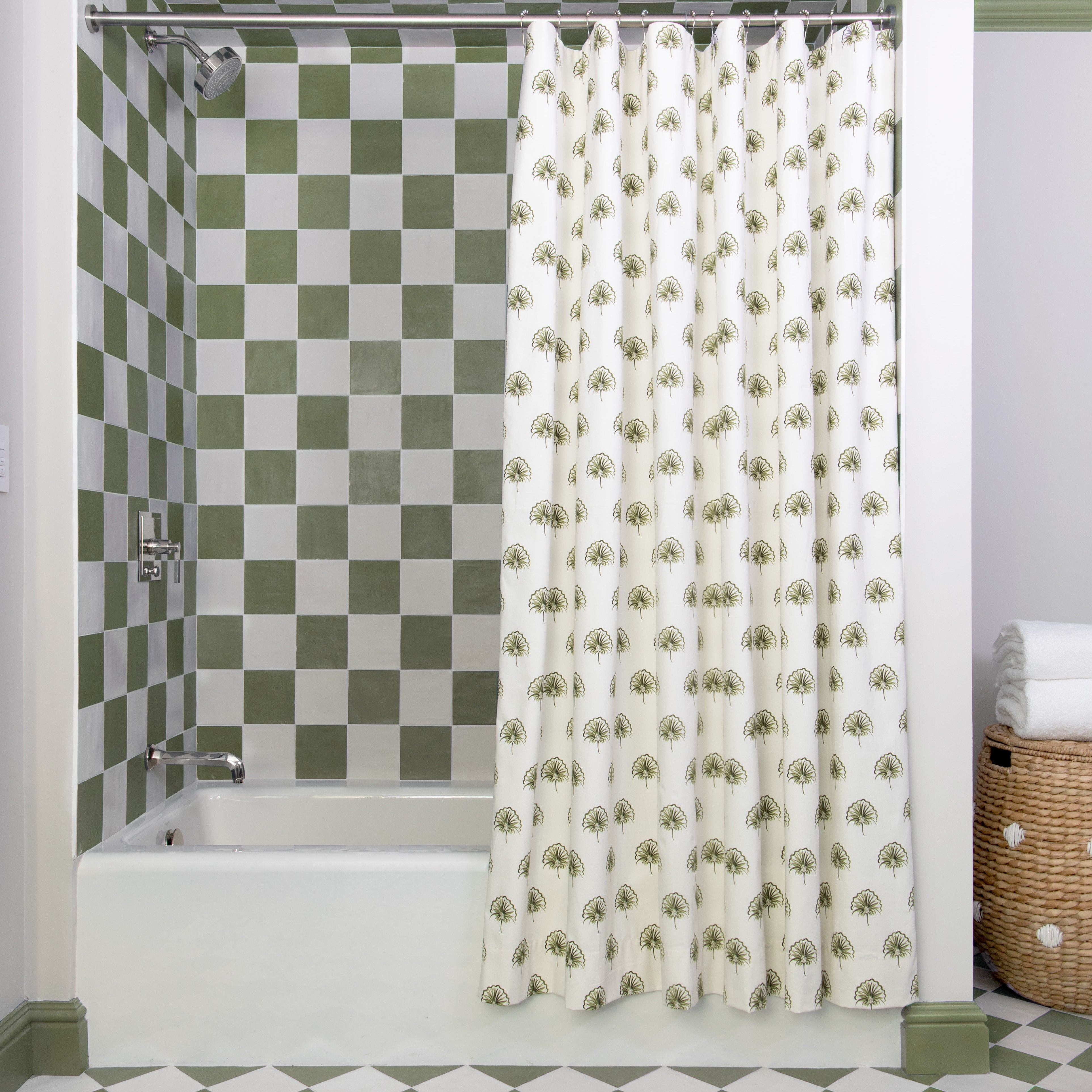 Green Floral Printed shower curtain hanging on rod in front of white tub in bathroom with green and white tiles